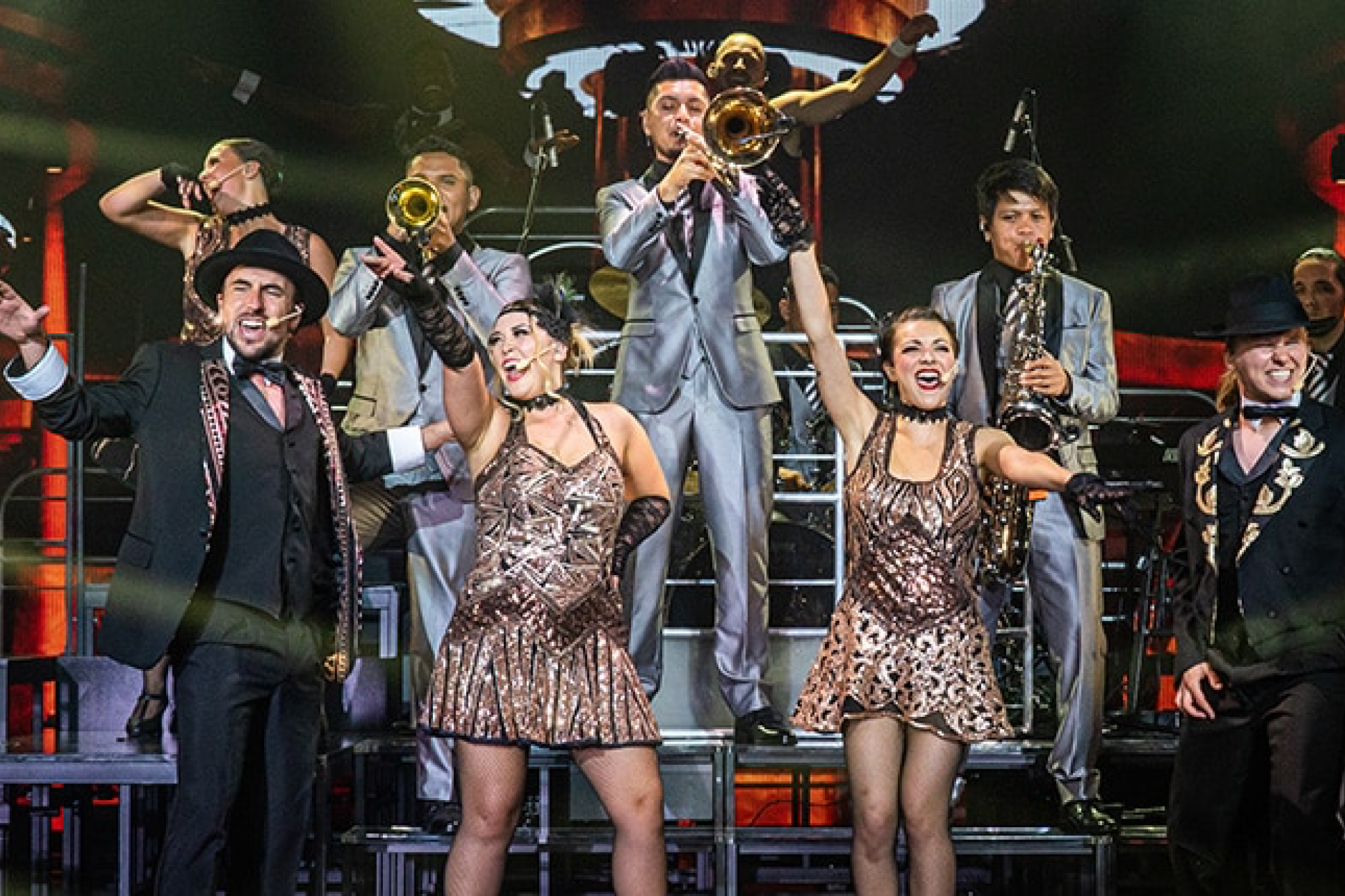 Live performance on Carnival Firenze featuring singers, dancers, and musicians in an onboard theater production with 1920s-style costumes.