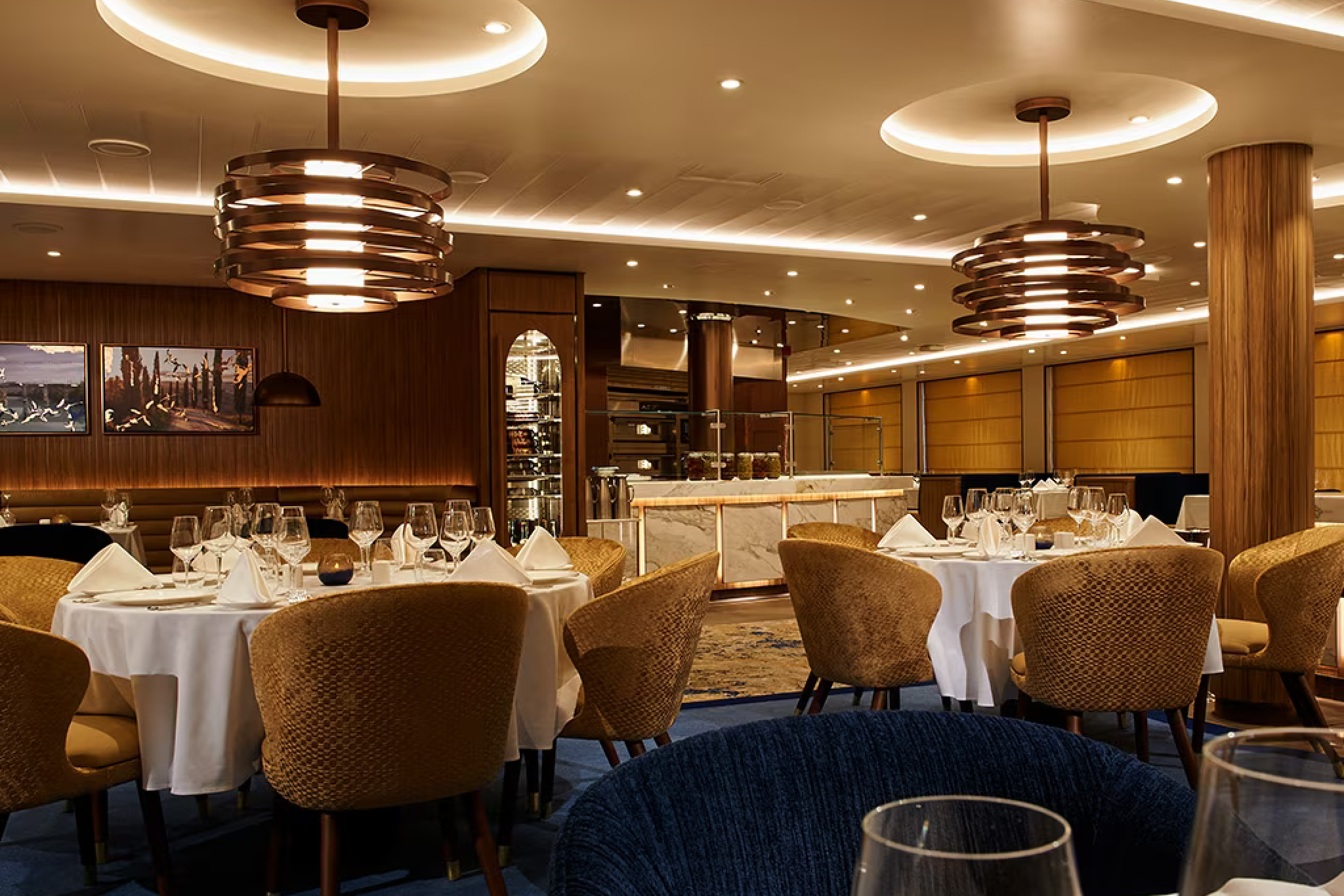 Elegant main dining room aboard Carnival Venezia with modern lighting, set tables, and warm décor.