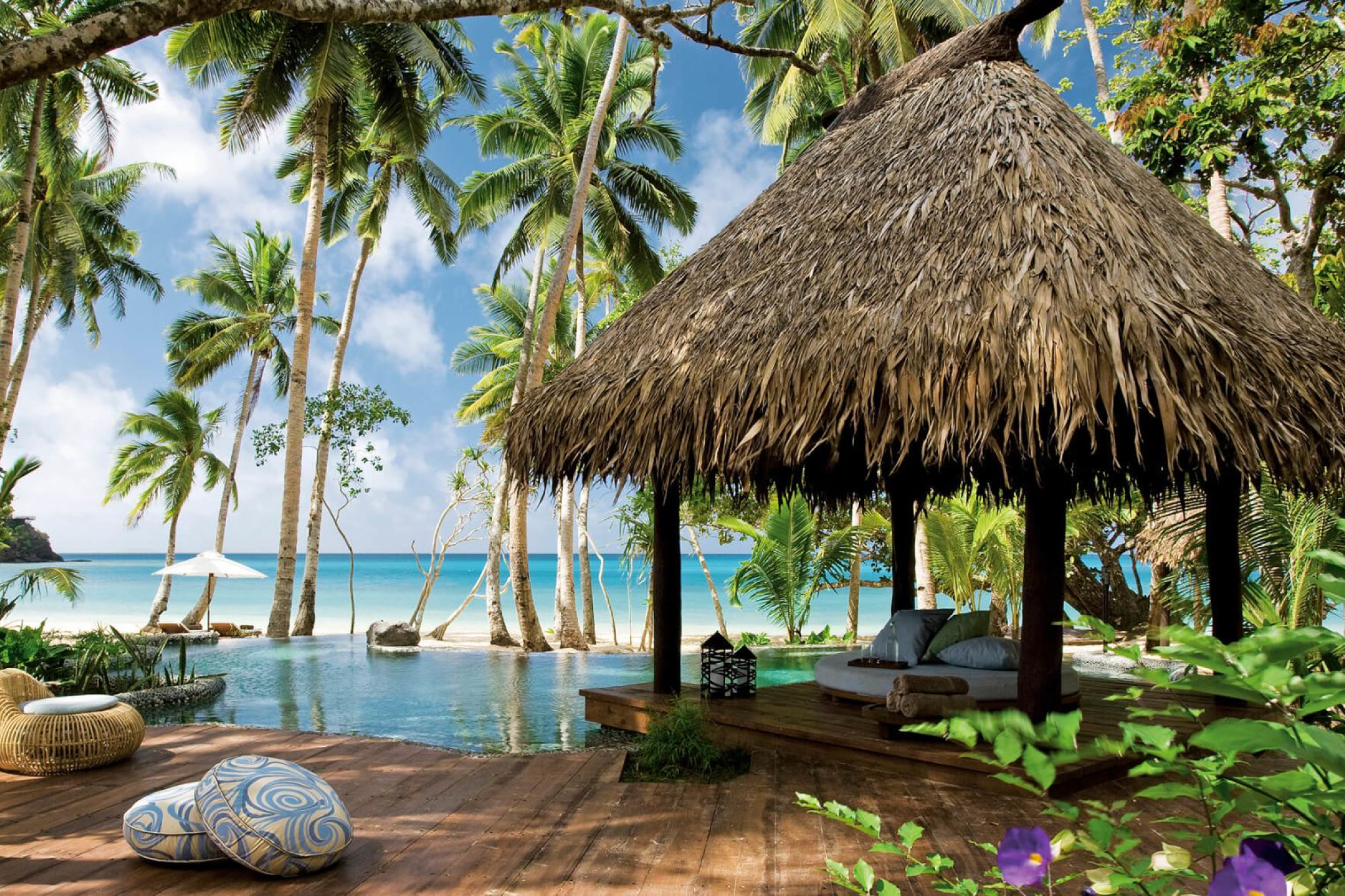 Beachfront cabana and palm-lined infinity pool at COMO Laucala Island, offering tropical luxury and ocean views.