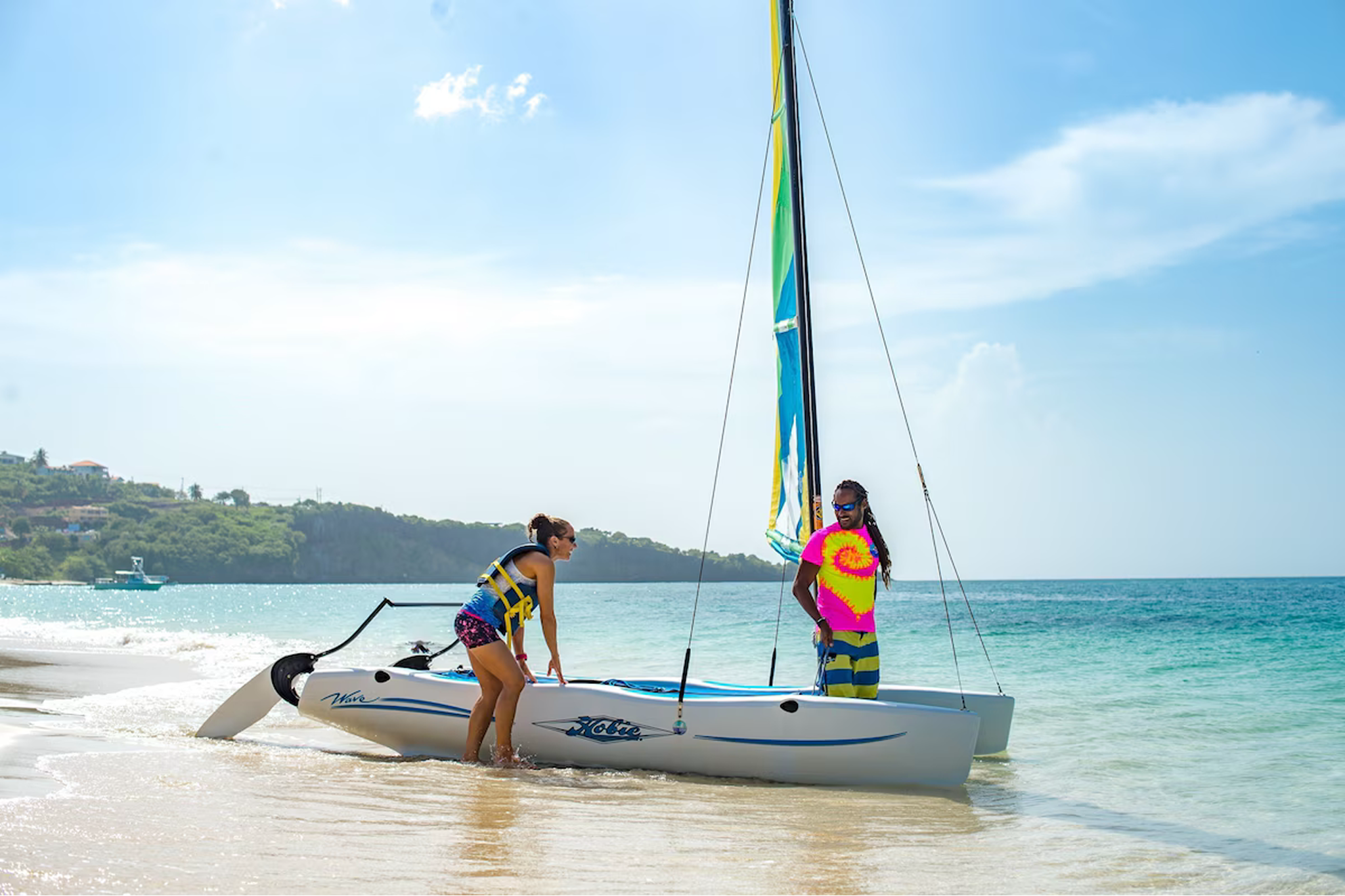 Guests preparing for a Hobie Cat sail along the shore of Grand Anse Beach at Coyaba Beach Resort.