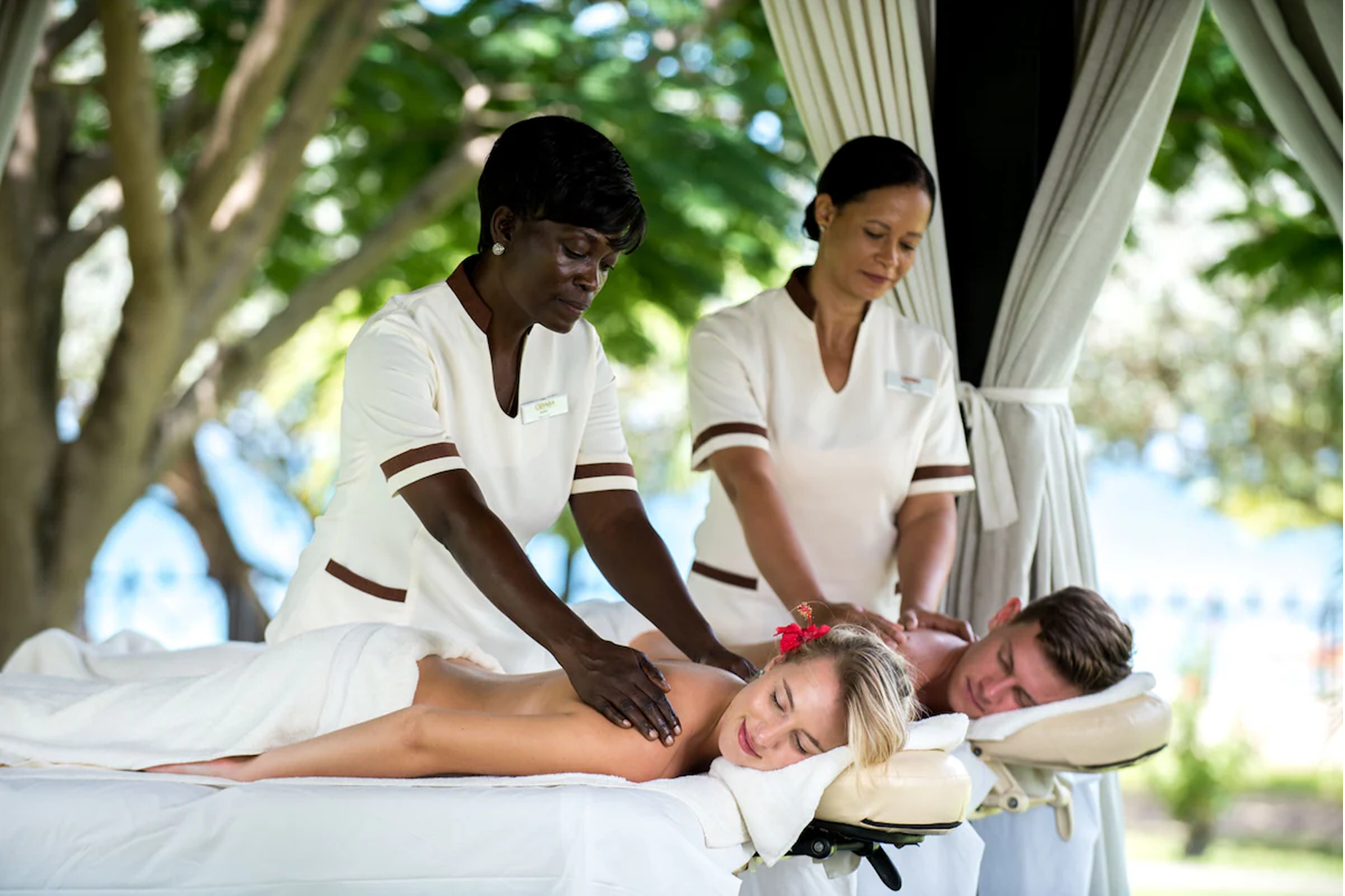 Guests enjoying open-air couples massage in the spa pavilion at Coyaba Beach Resort, set amid lush greenery.