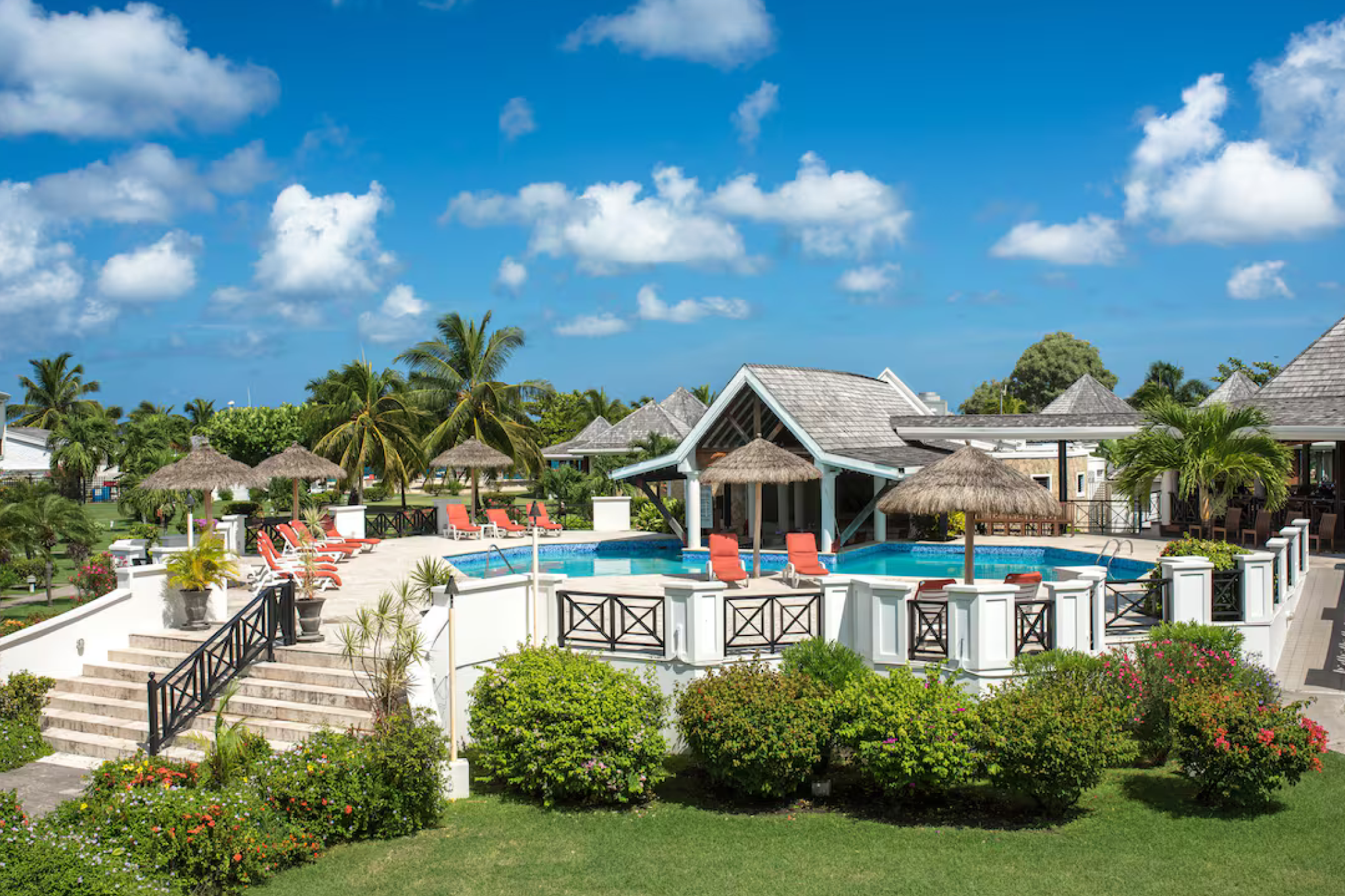 A scenic view of the pool area at Coyaba Beach Resort, surrounded by tropical gardens and Caribbean-style architecture.