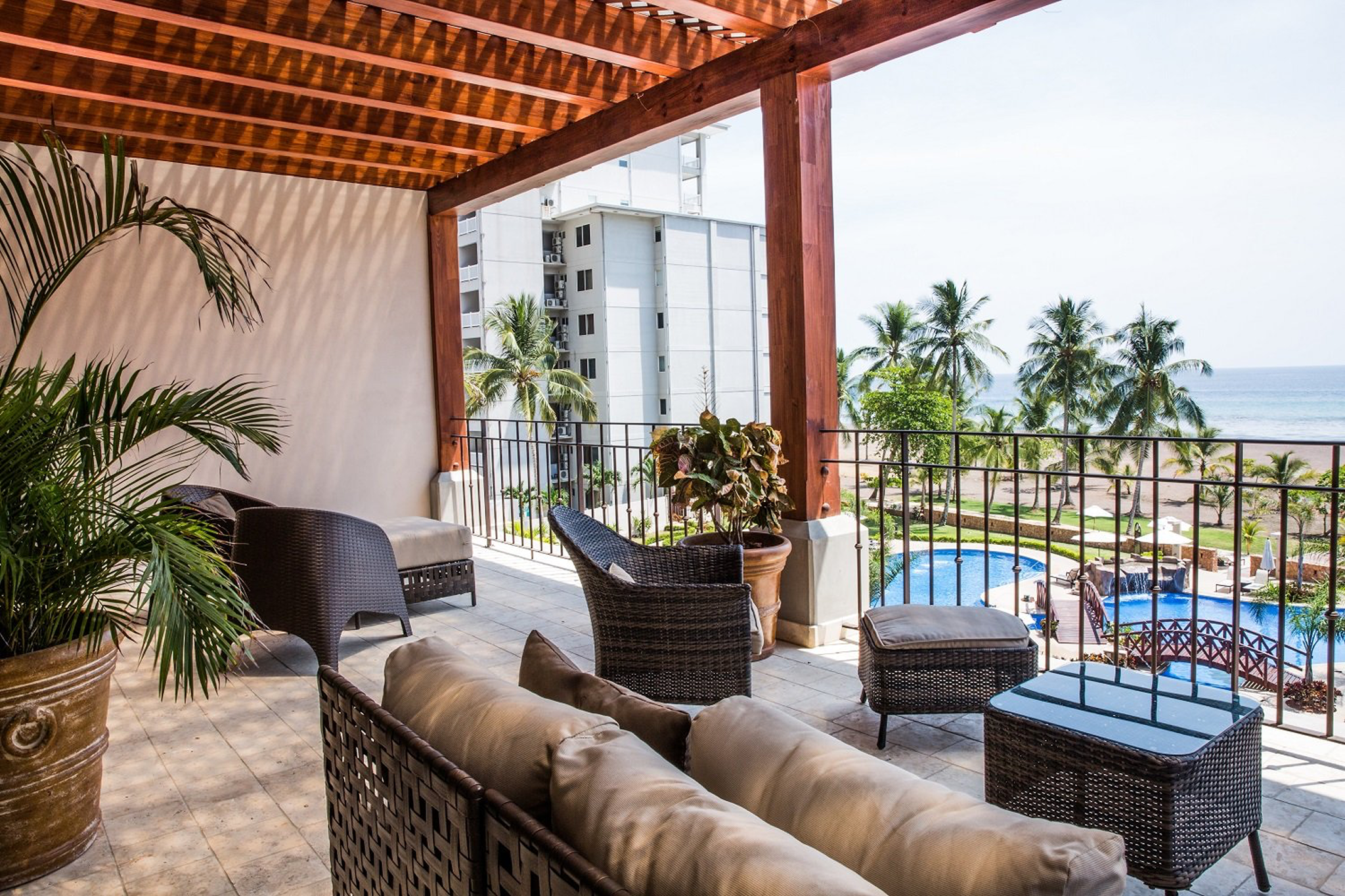Furnished balcony at Crocs Resort & Casino overlooking the pool and beach, with rattan seating and tropical landscaping.