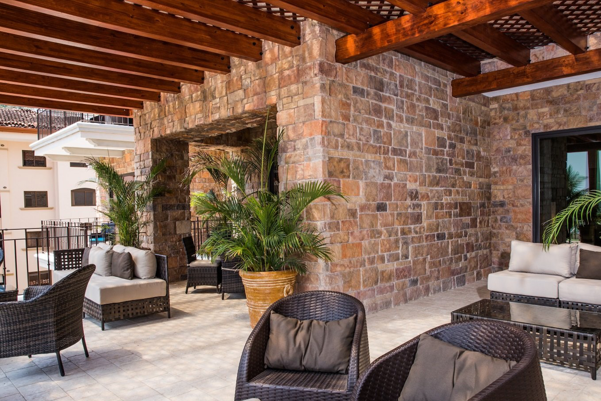 Shaded outdoor lounge area at Crocs Resort & Casino featuring stone walls, wooden beams, and comfortable seating.