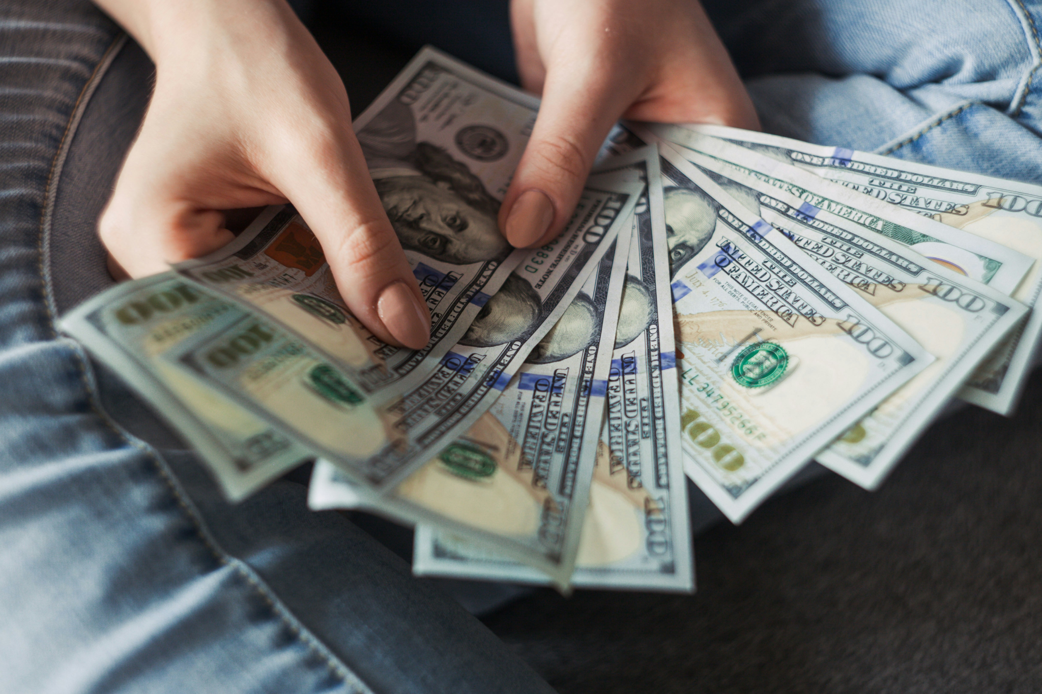 Hands holding U.S. dollar bills, representing cruise myths that portray cruising as unaffordable despite its bundled value and inclusions.