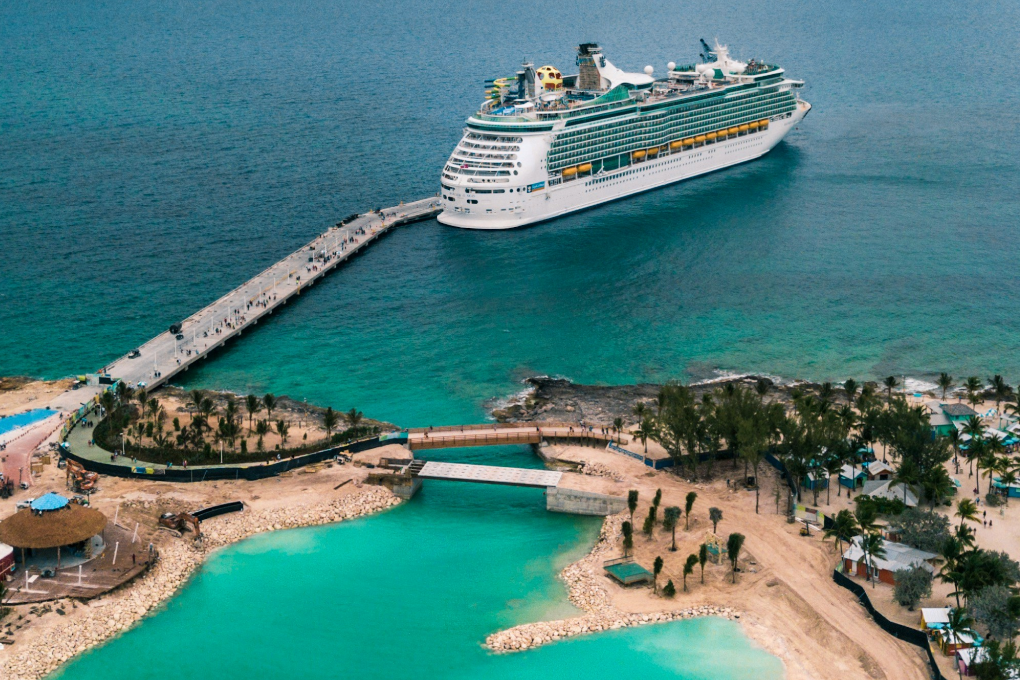 A cruise ship docked at a tropical port with passengers disembarking, addressing cruise myths that port visits are too short to enjoy.
