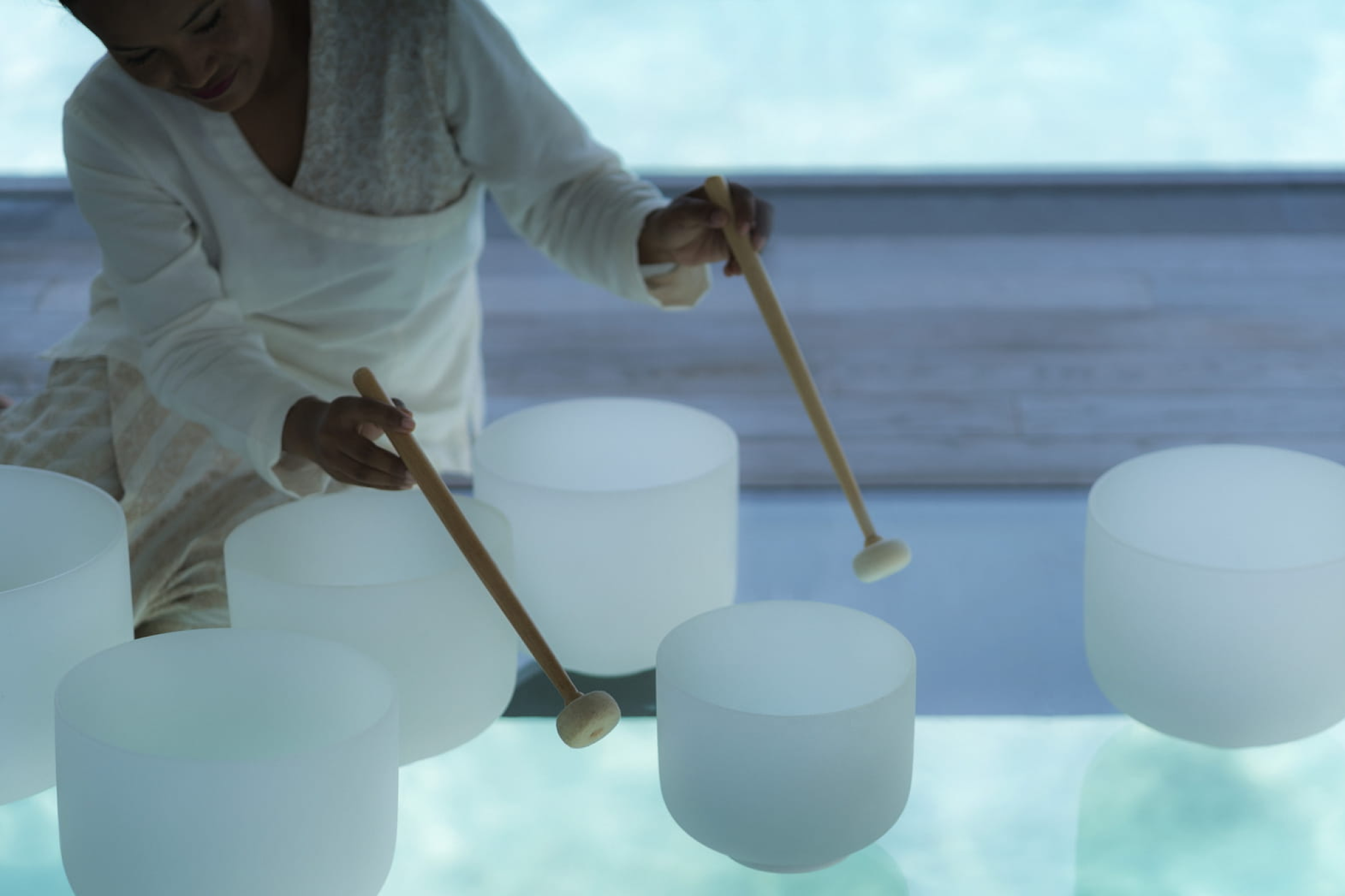 Wellness therapist playing crystal singing bowls during a private sound therapy session at Voavah.