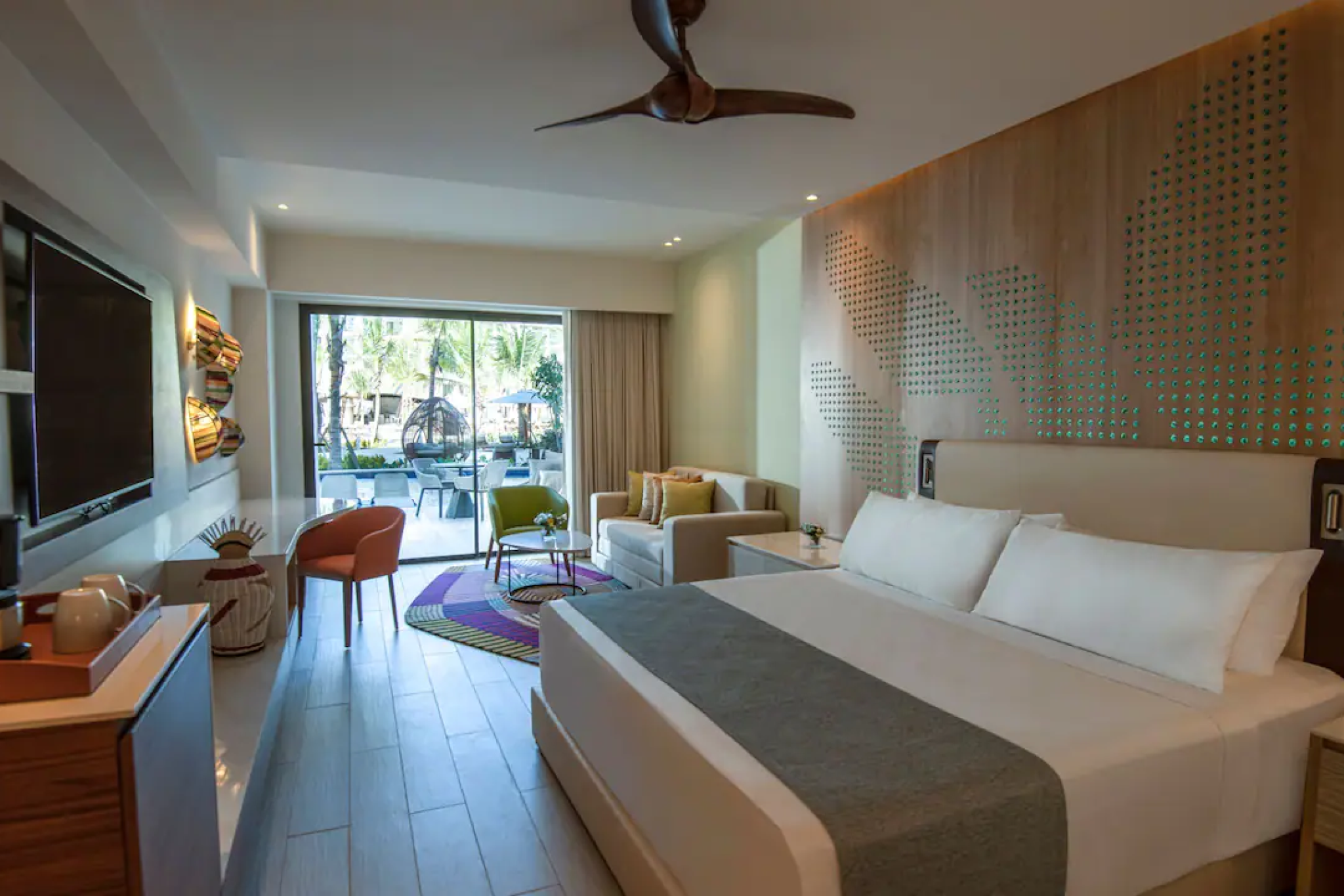 Spacious modern guest room at Hyatt Ziva Cap Cana with king bed, cozy seating area, and a view of the private terrace.