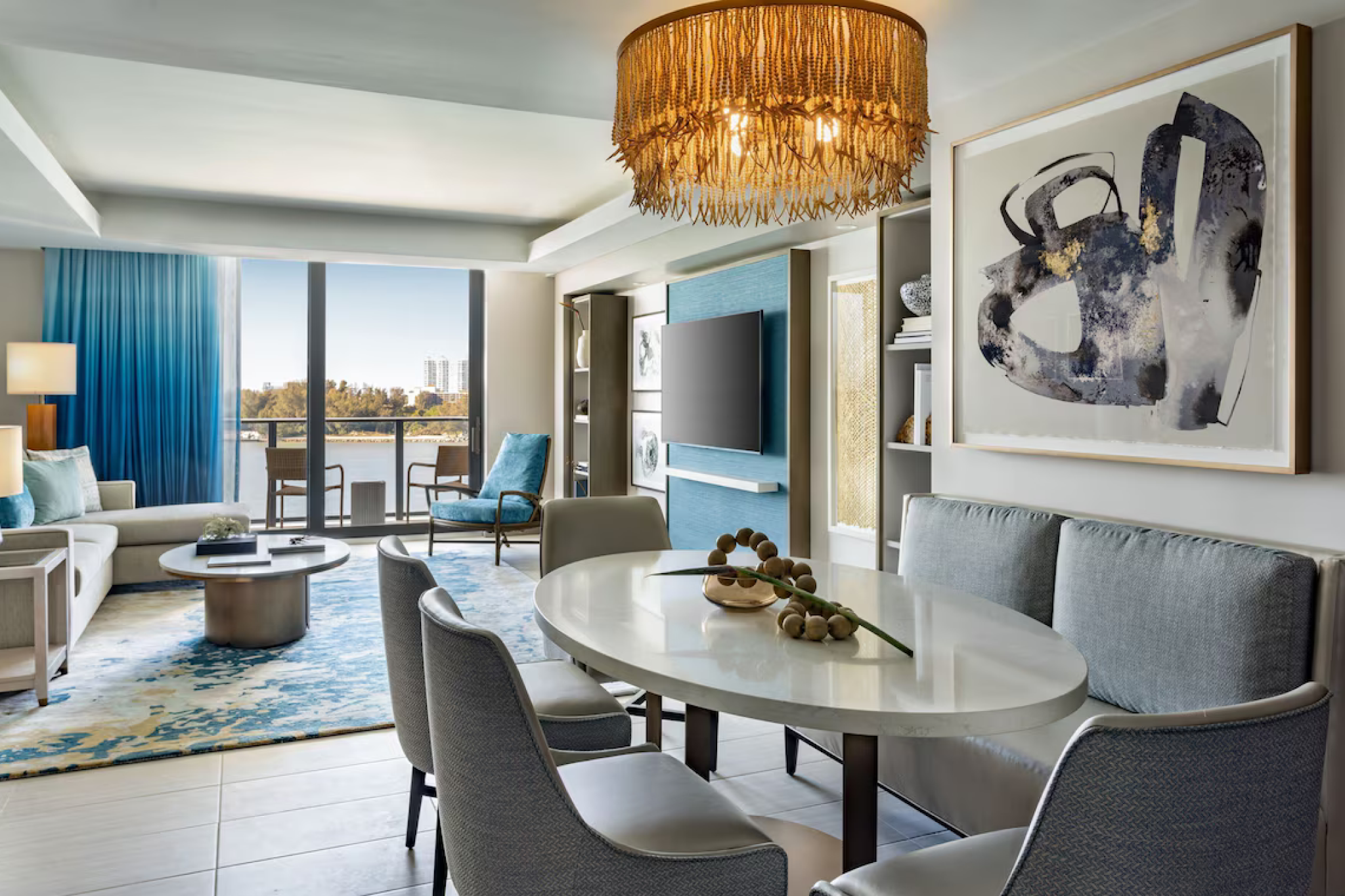 Sophisticated guest suite at JW Marriott Clearwater Beach Resort & Spa boasting ocean-inspired design elements, a contemporary dining area, and private balcony with scenic views of the water and surrounding cityscape.