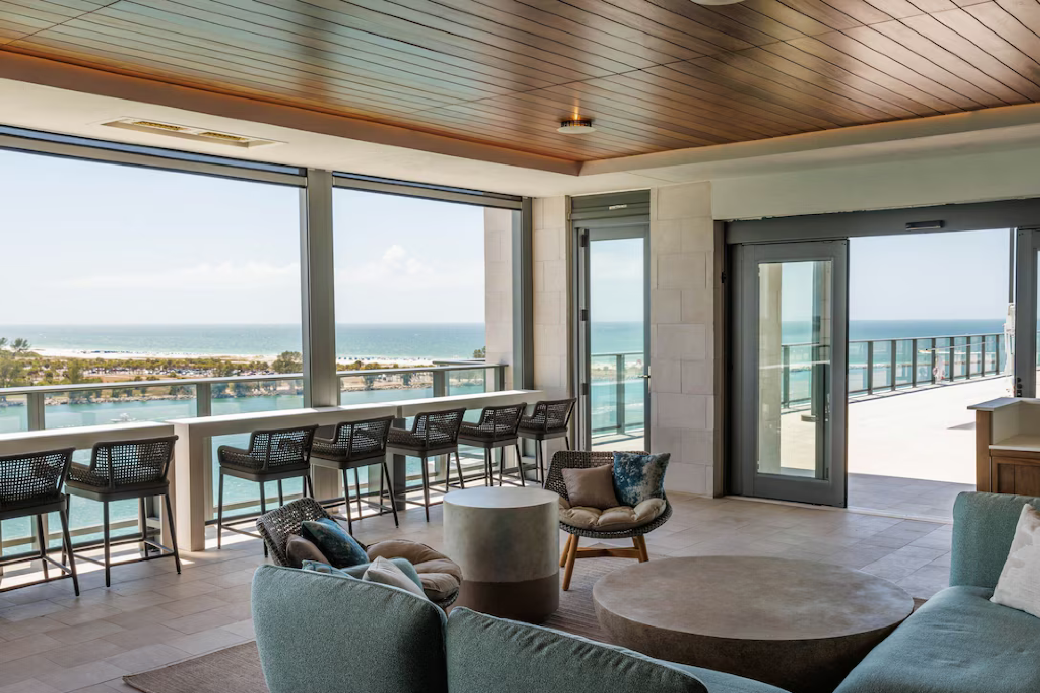 Elegant indoor lounge at JW Marriott Clearwater Beach Resort & Spa featuring modern coastal decor, plush seating, and expansive floor-to-ceiling windows offering panoramic views of the Gulf of Mexico and Intracoastal Waterway.