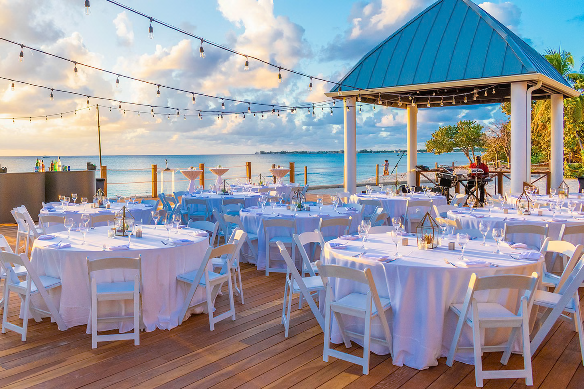 Outdoor dining area at Kimpton Seafire Resort + Spa overlooking the Caribbean Sea, with neatly arranged tables and ambient lighting.