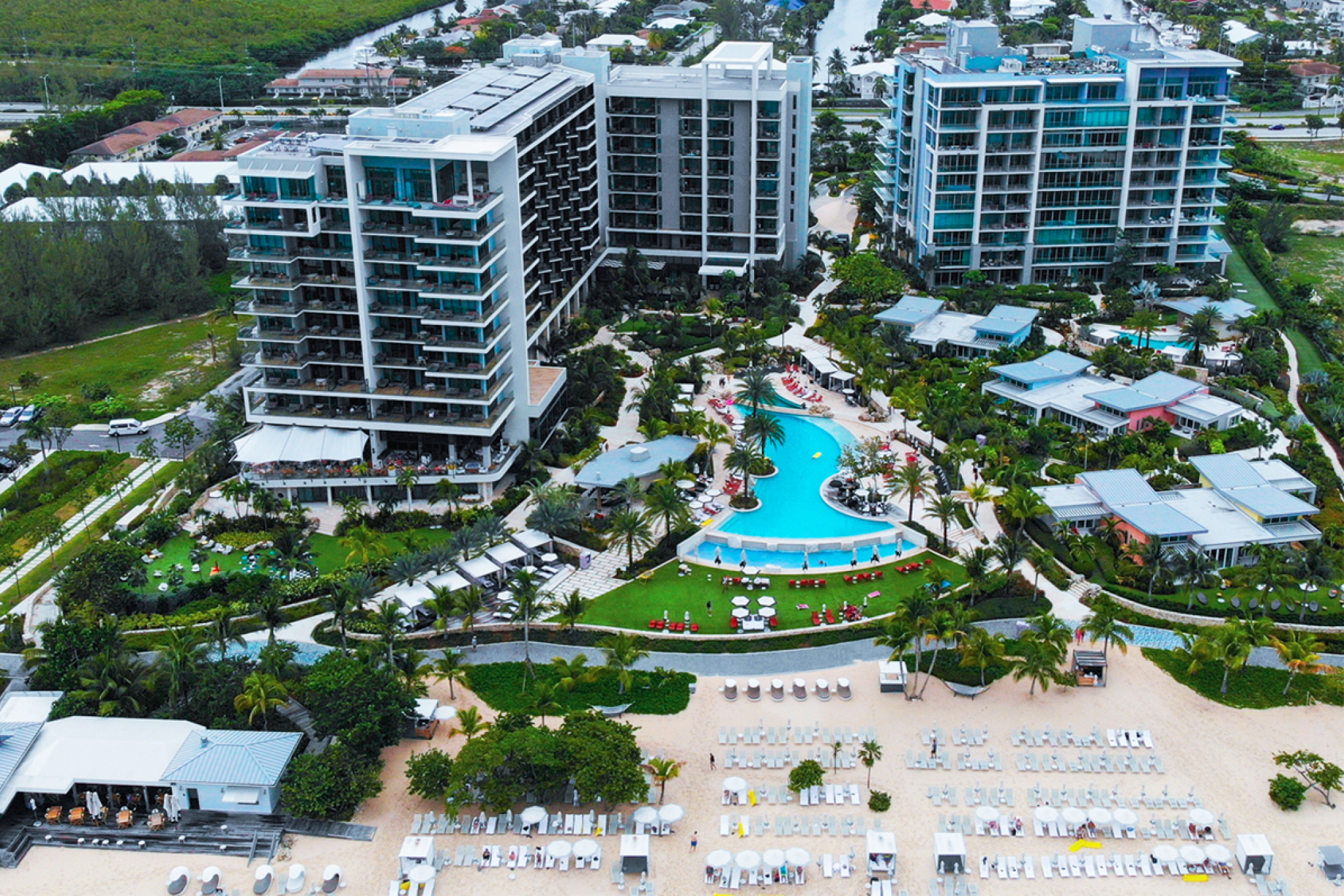 Aerial view of Kimpton Seafire Resort + Spa on Grand Cayman, with white sand beach, turquoise waters, and lush tropical landscaping.