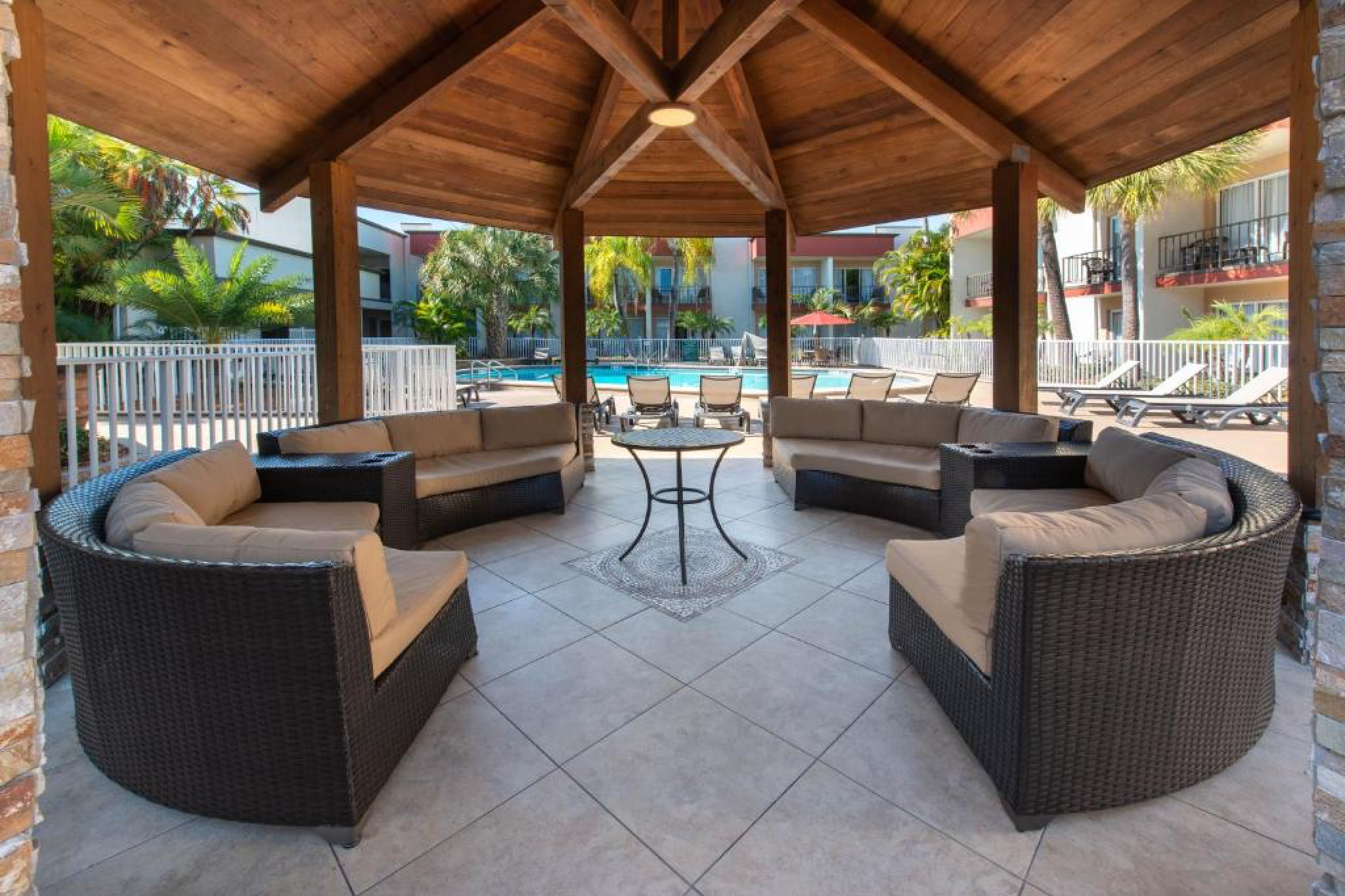 Shaded outdoor seating pavilion with wicker sofas overlooking the pool at la quinta inn by wyndham clearwater central.