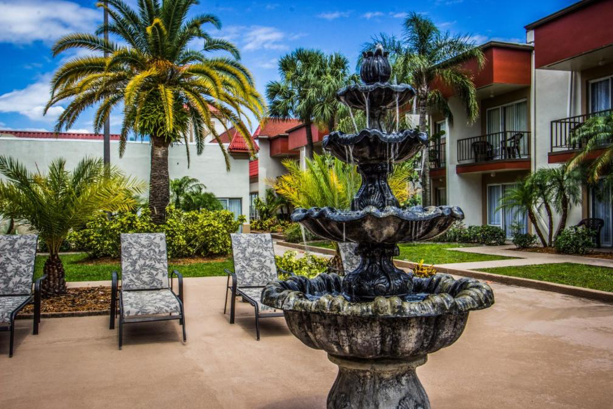 Tranquil courtyard with tiered stone fountain and tropical landscaping at la quinta inn by wyndham clearwater central.