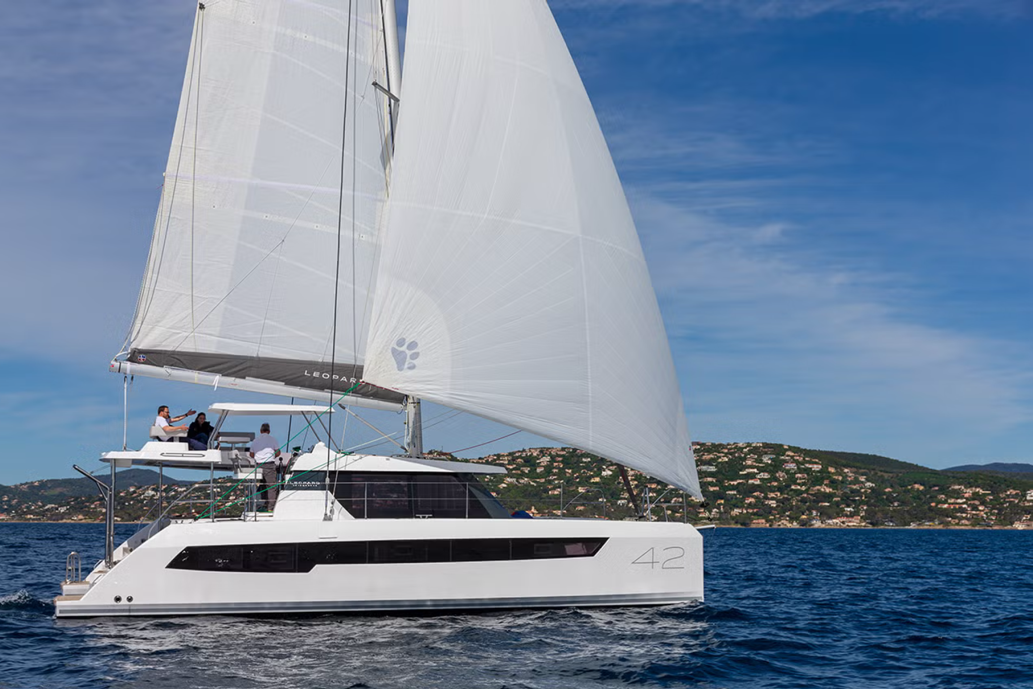 The Leopard 42 catamaran sailing in open water with full sails, showing its sleek design and spacious upper deck.