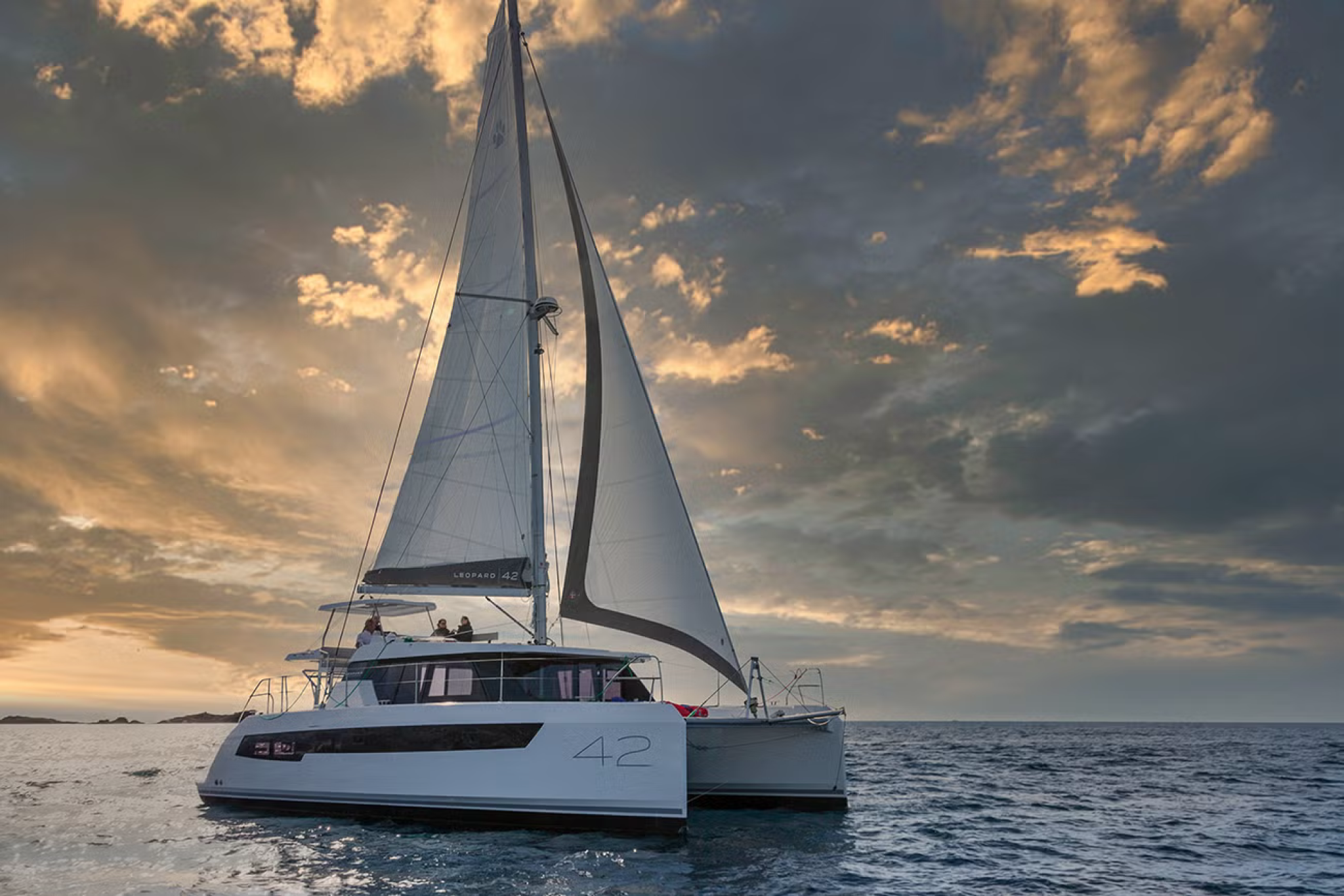 The Leopard 42 catamaran under sail at sunset, highlighting its clean lines and dual-hull silhouette against dramatic skies.