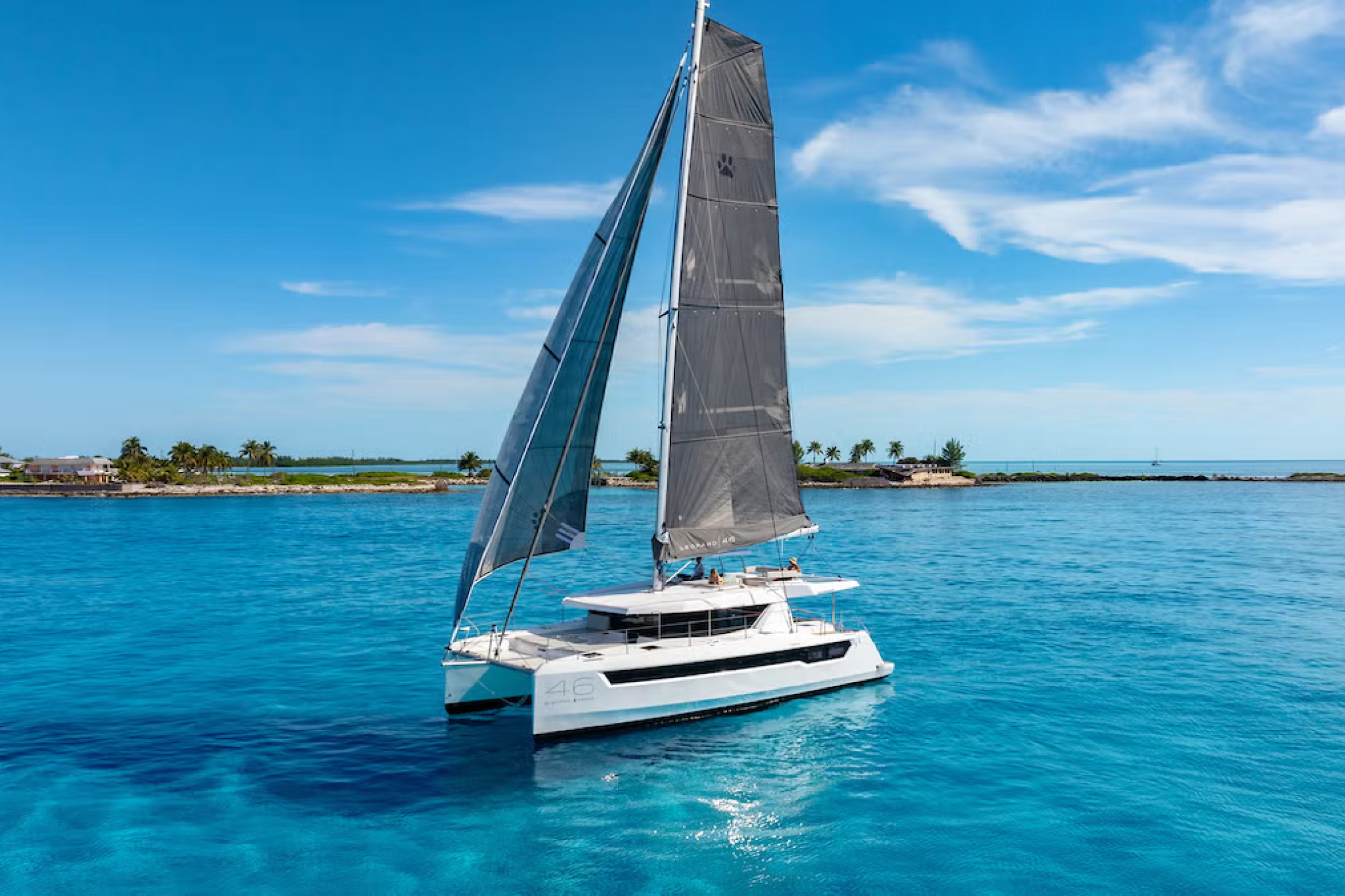 Leopard 46 sailing catamaran underway with full sails up, demonstrating performance and stability in open water near a coastal shoreline