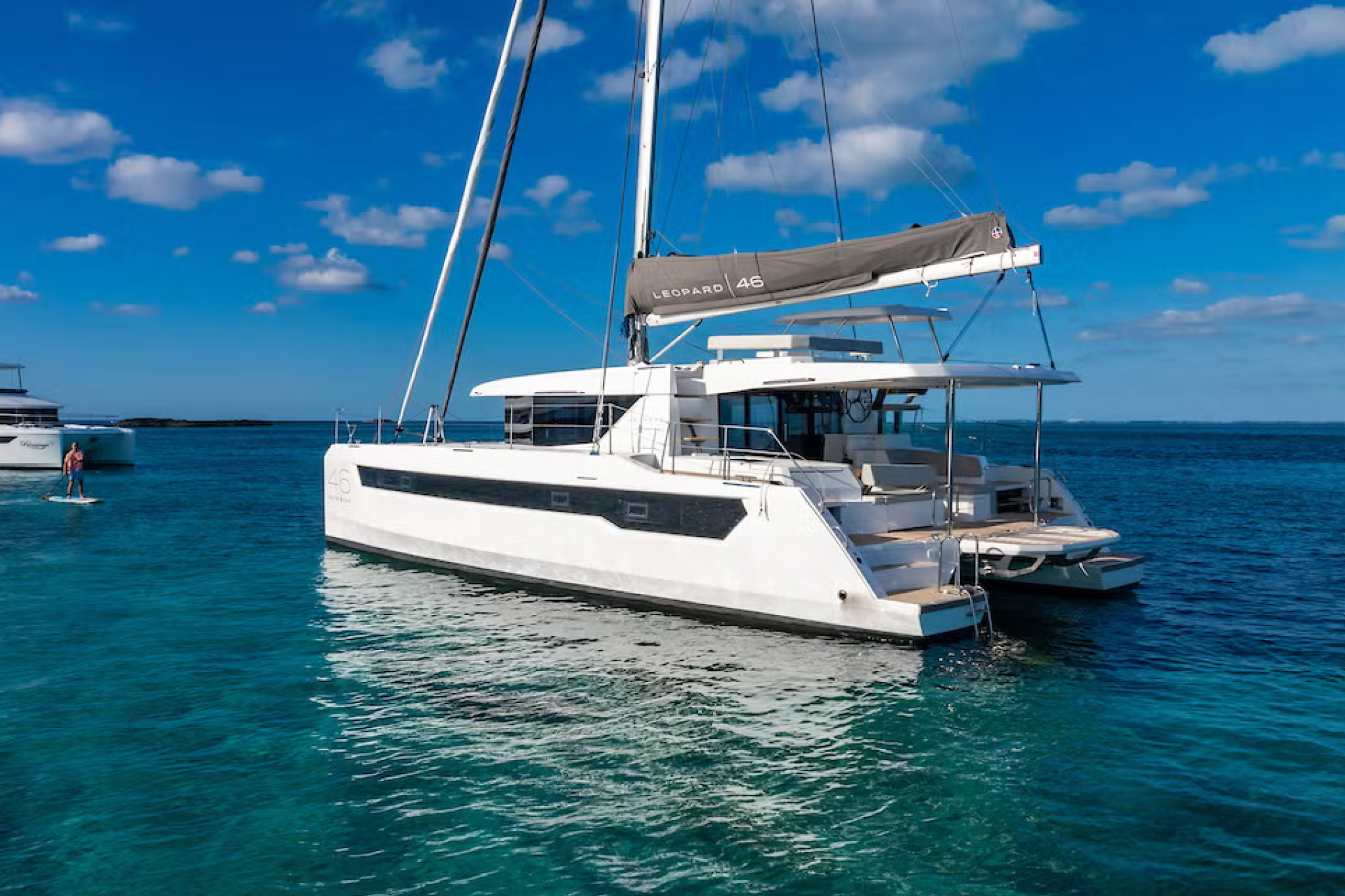 The Leopard 46 sailing catamaran anchored in shallow turquoise water, with people relaxing on deck, showcasing the spacious foredeck and lounging areas