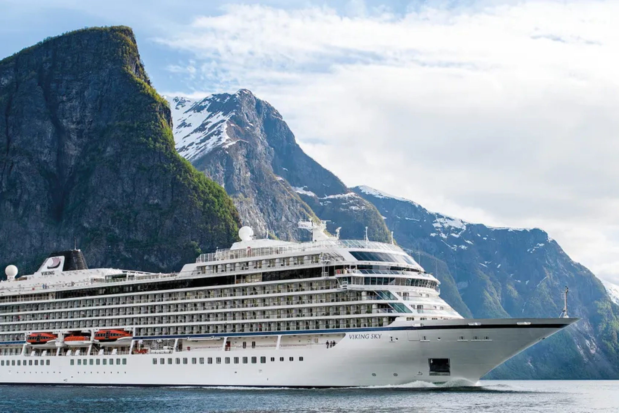 Major ocean cruise ships debuting in 2026 showcased by Viking Libra sailing near mountainous terrain, highlighting its streamlined exterior, all-veranda stateroom layout, and emphasis on quiet, sustainable ocean cruising