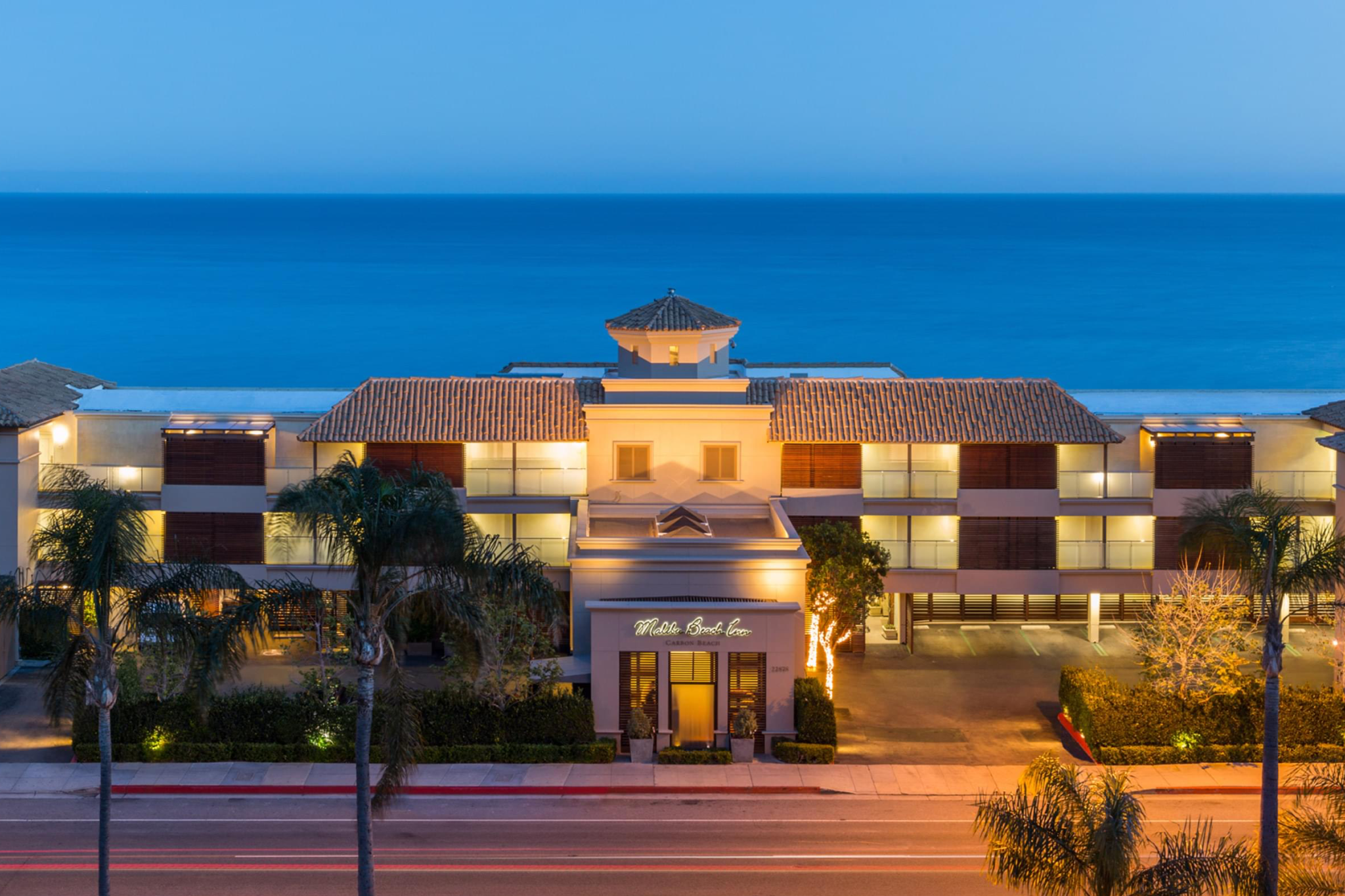 Front exterior of Malibu Beach Inn at dusk with ocean backdrop