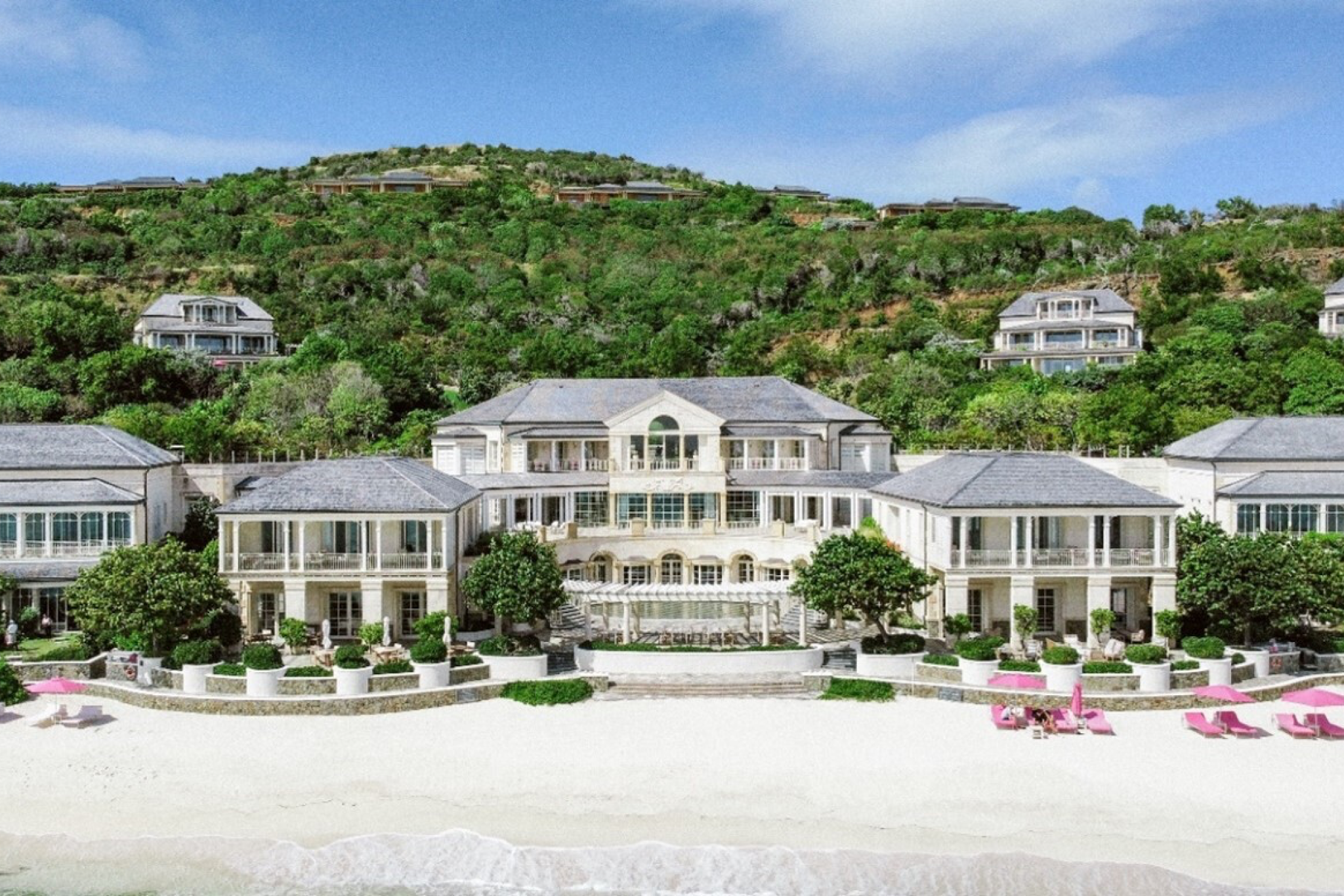 Aerial view of Mandarin Oriental Canouan surrounded by lush hills and turquoise water, setting the tone for its secluded Caribbean luxury.