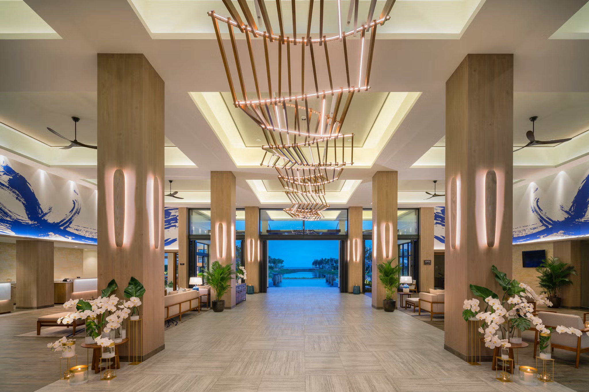 Open-air lobby at Melia Ho Tram Beach Resort with modern decor, high ceilings, and views of palm trees and the ocean.