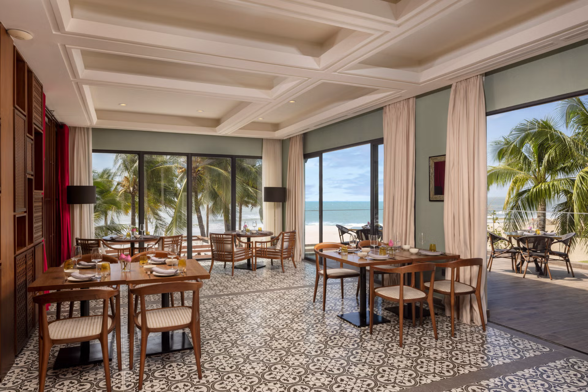 Elegant seaside restaurant at Melia Ho Tram Beach Resort with neatly set tables and panoramic views of the beach.