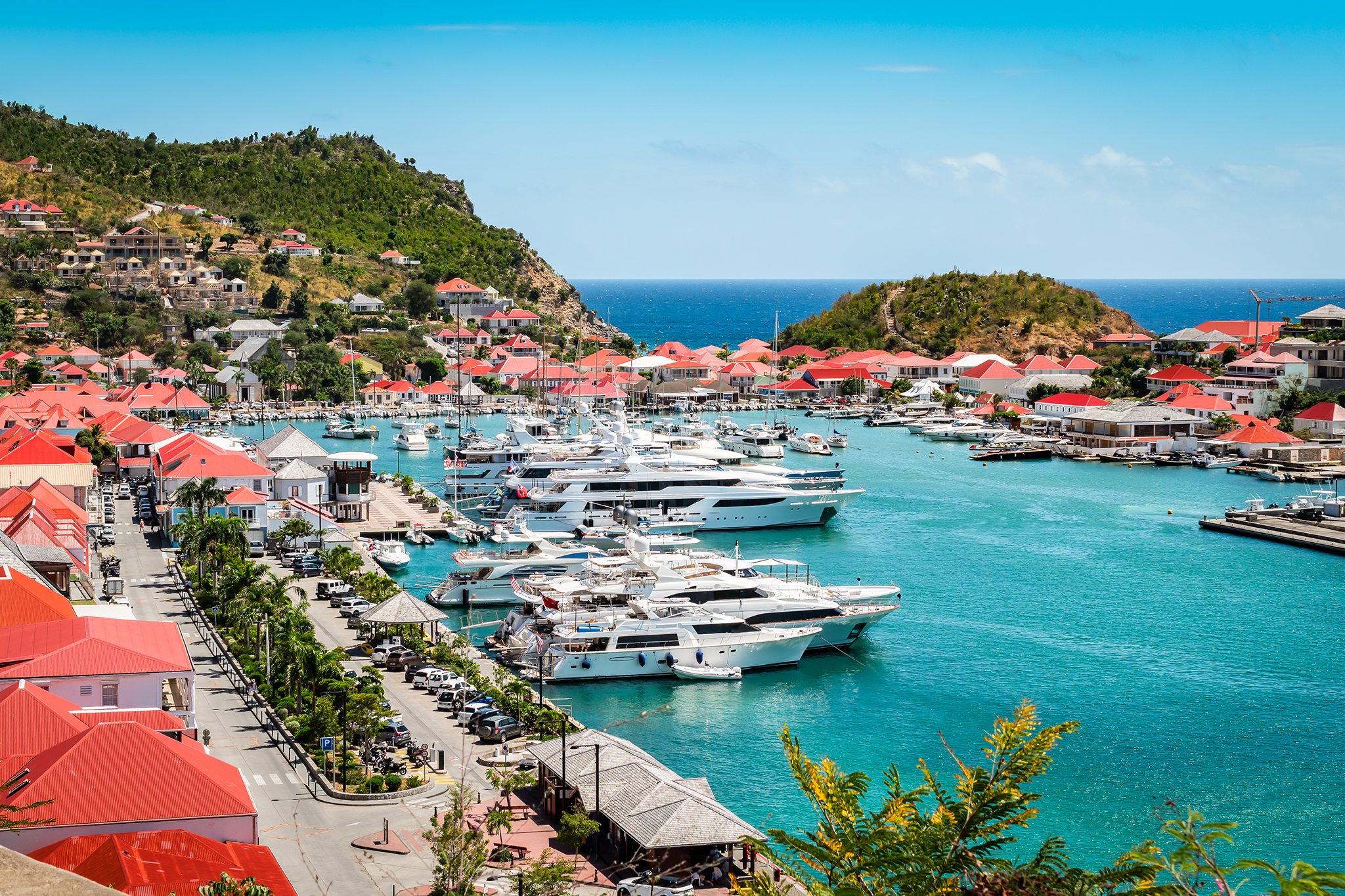 Stunning turquoise harbor in St. Barts with red-roofed buildings and luxury yachts, one of the most scenic Caribbean islands