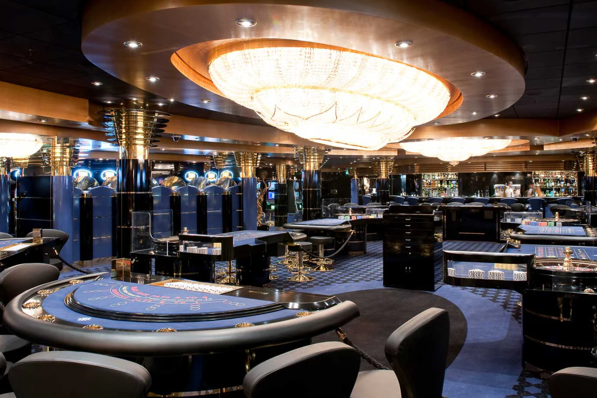Luxurious onboard casino on MSC Magnifica with poker tables, slot machines, and a grand crystal chandelier.