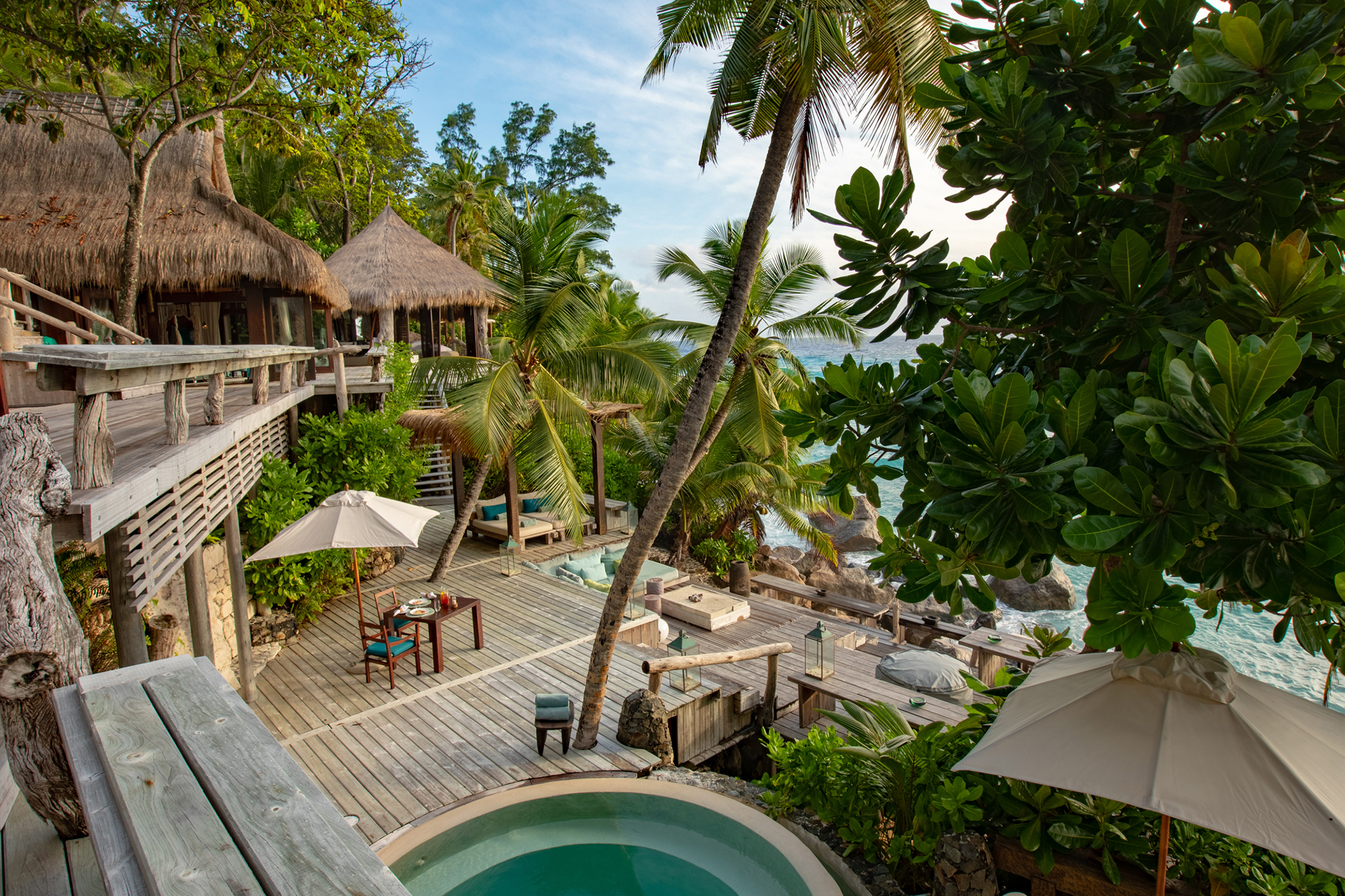 Secluded deck at North Island Seychelles with a private plunge pool, outdoor dining area, and panoramic ocean views framed by palm trees.