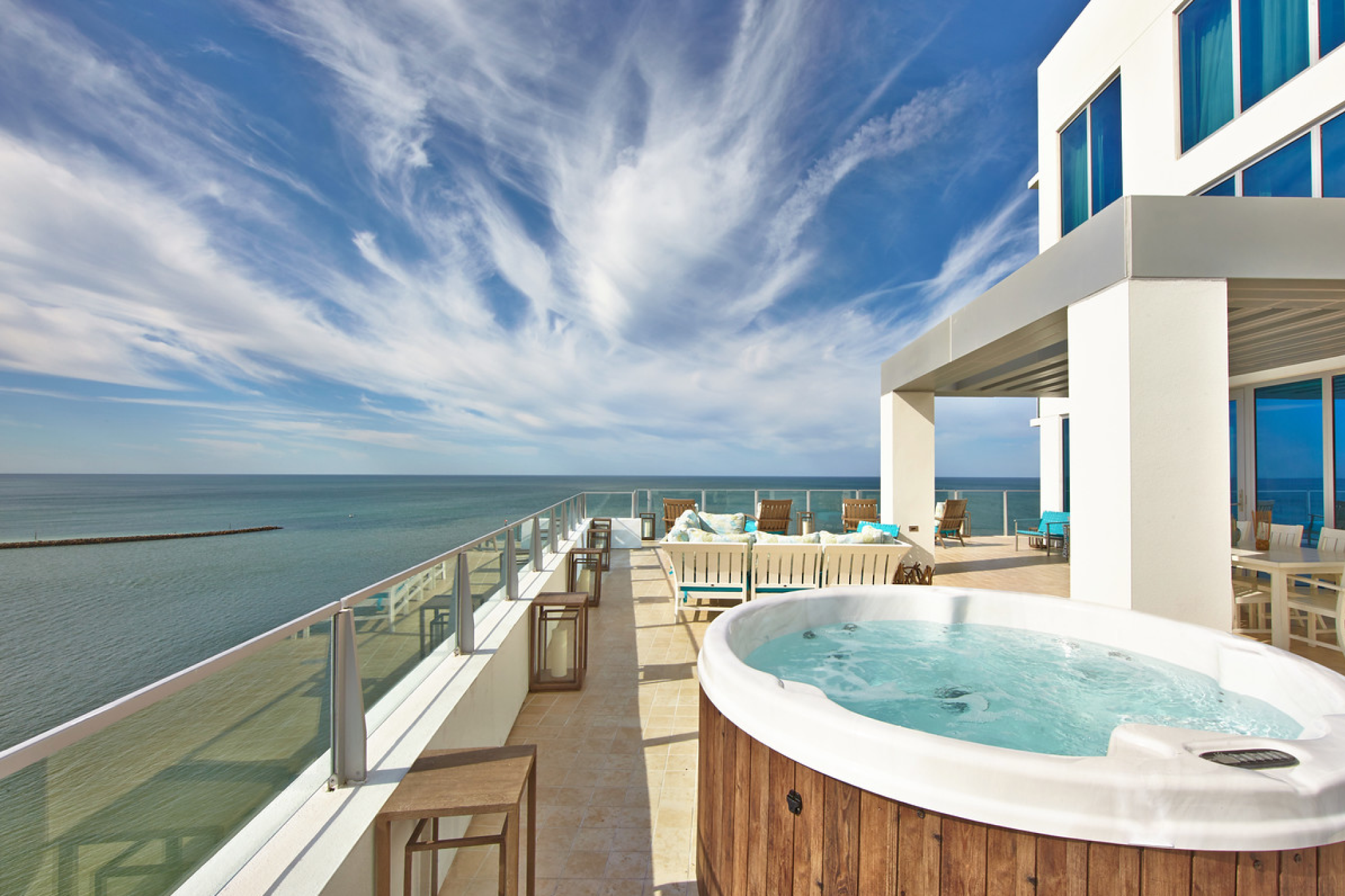 Private ocean-view terrace with a whirlpool hot tub and stylish lounge seating at Opal Sands Resort, overlooking the calm waters of the Gulf.