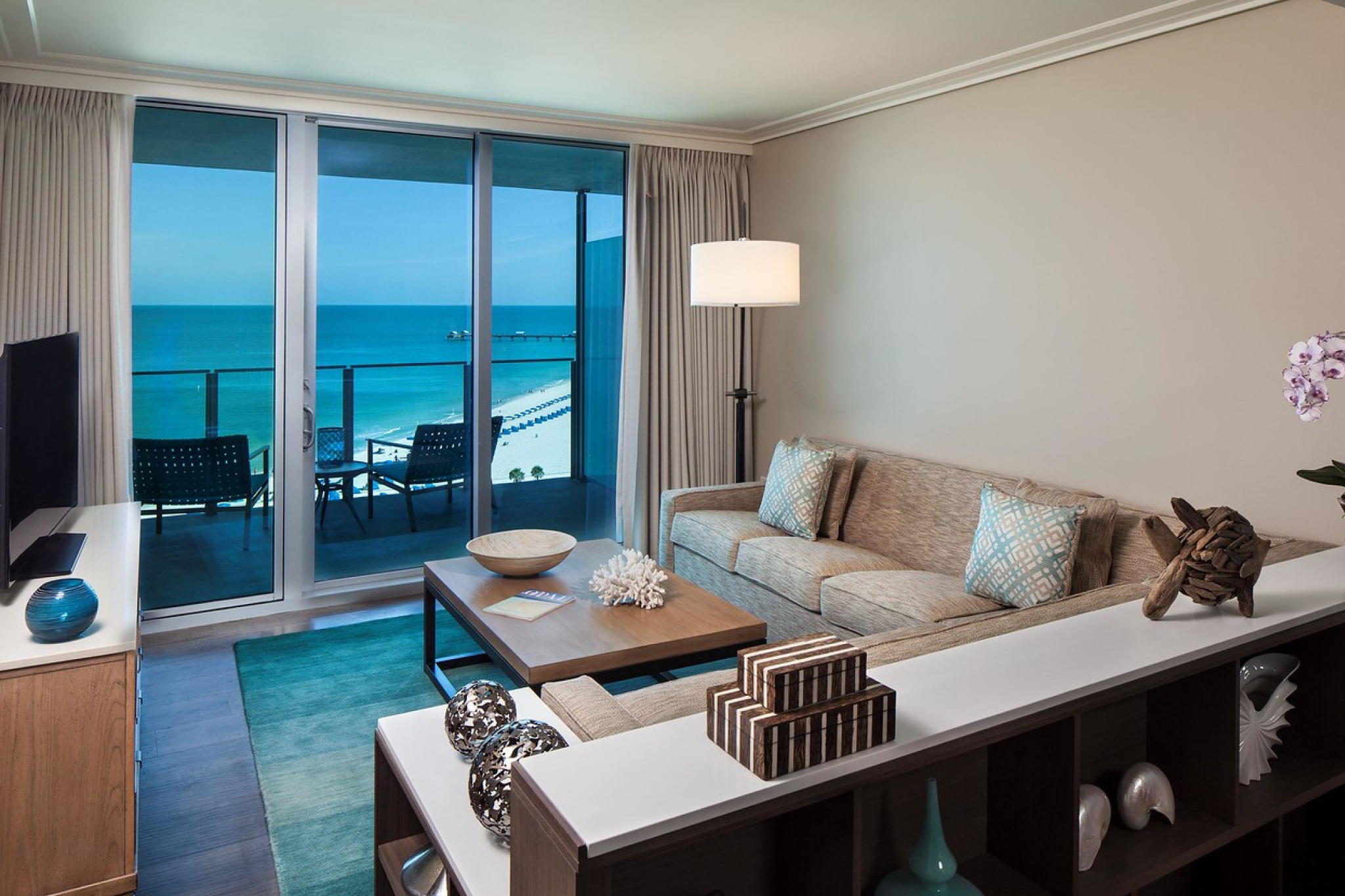 Elegant guest suite at Opal Sands Resort with a private balcony and sweeping views of the turquoise Gulf of Mexico shoreline.