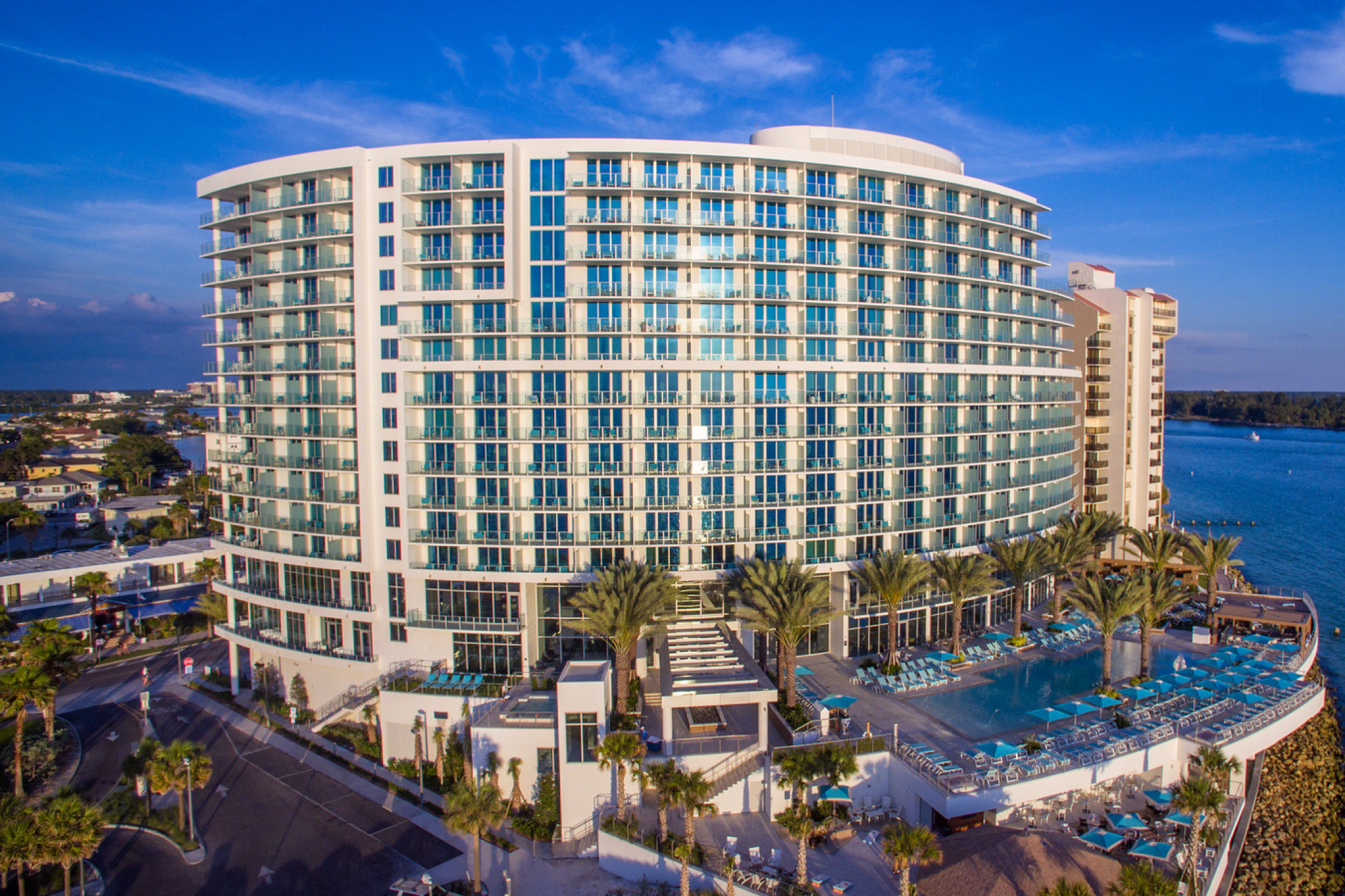 Striking curved façade of Opal Sands Resort in Clearwater Beach, framed by palm trees and the resort’s elevated Gulf-facing infinity pool.
