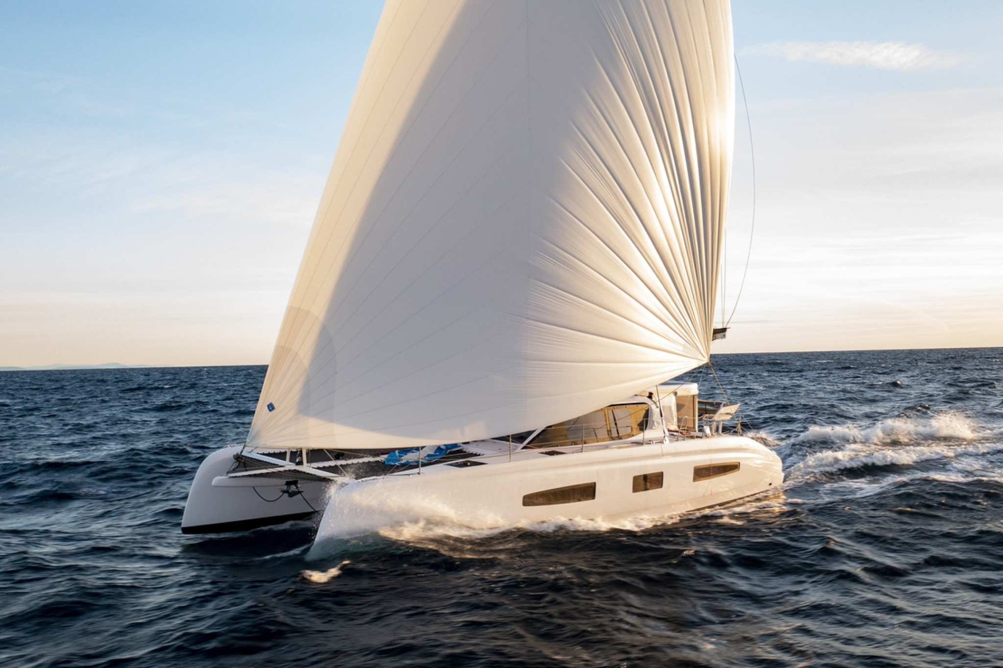 Outremer 52 catamaran sailing at speed with a large white sail in open water.
