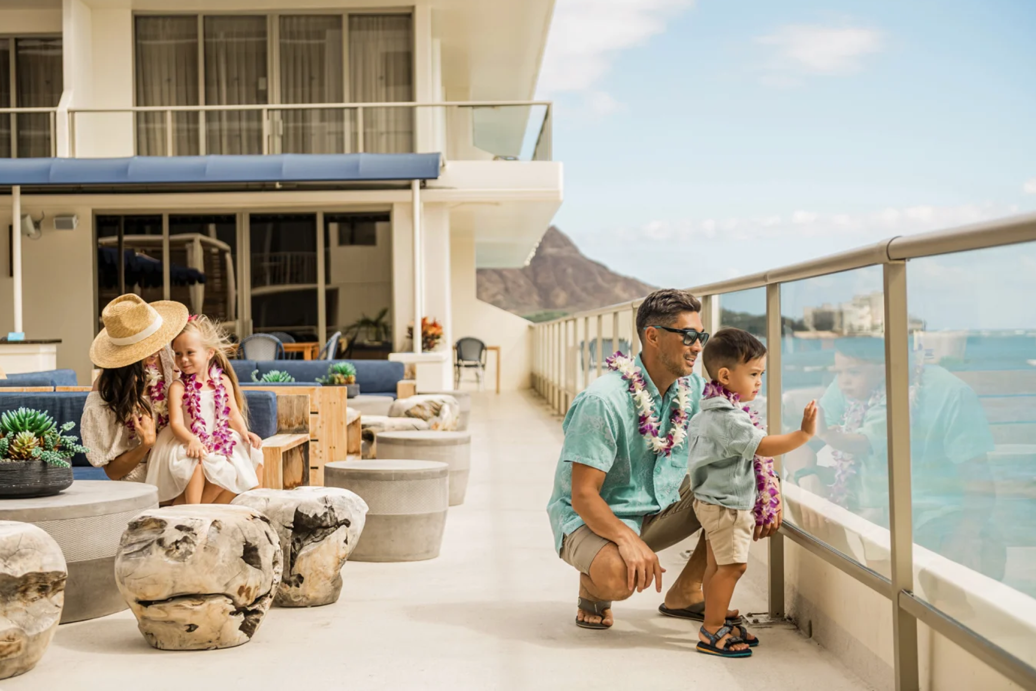 Family enjoying the Voyager 47 Club oceanfront terrace at Outrigger Reef Waikiki Beach Resort, with Diamond Head visible in the background.