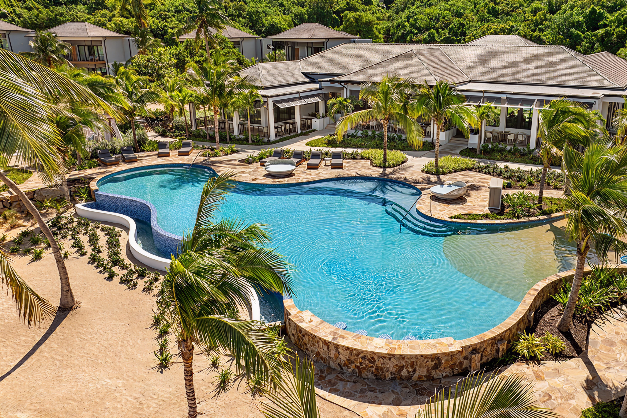 Main infinity pool surrounded by palm trees and luxury suites at Peter Island Resort in the British Virgin Islands, representing its exclusive luxury value.