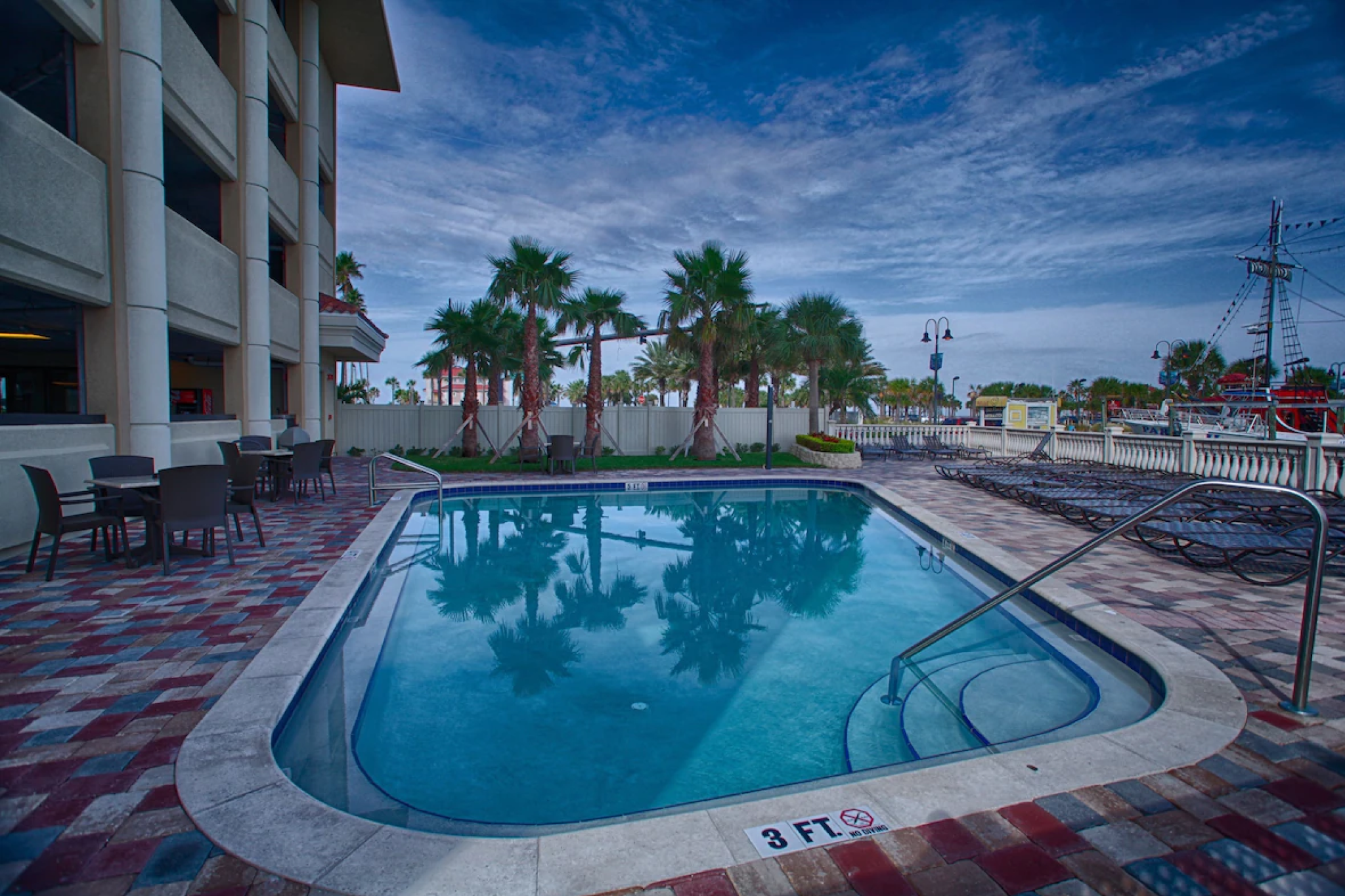 Outdoor pool at Pier House 60 Clearwater Beach Marina Hotel with palm trees, lounge chairs, and a view of the Clearwater Beach promenade.