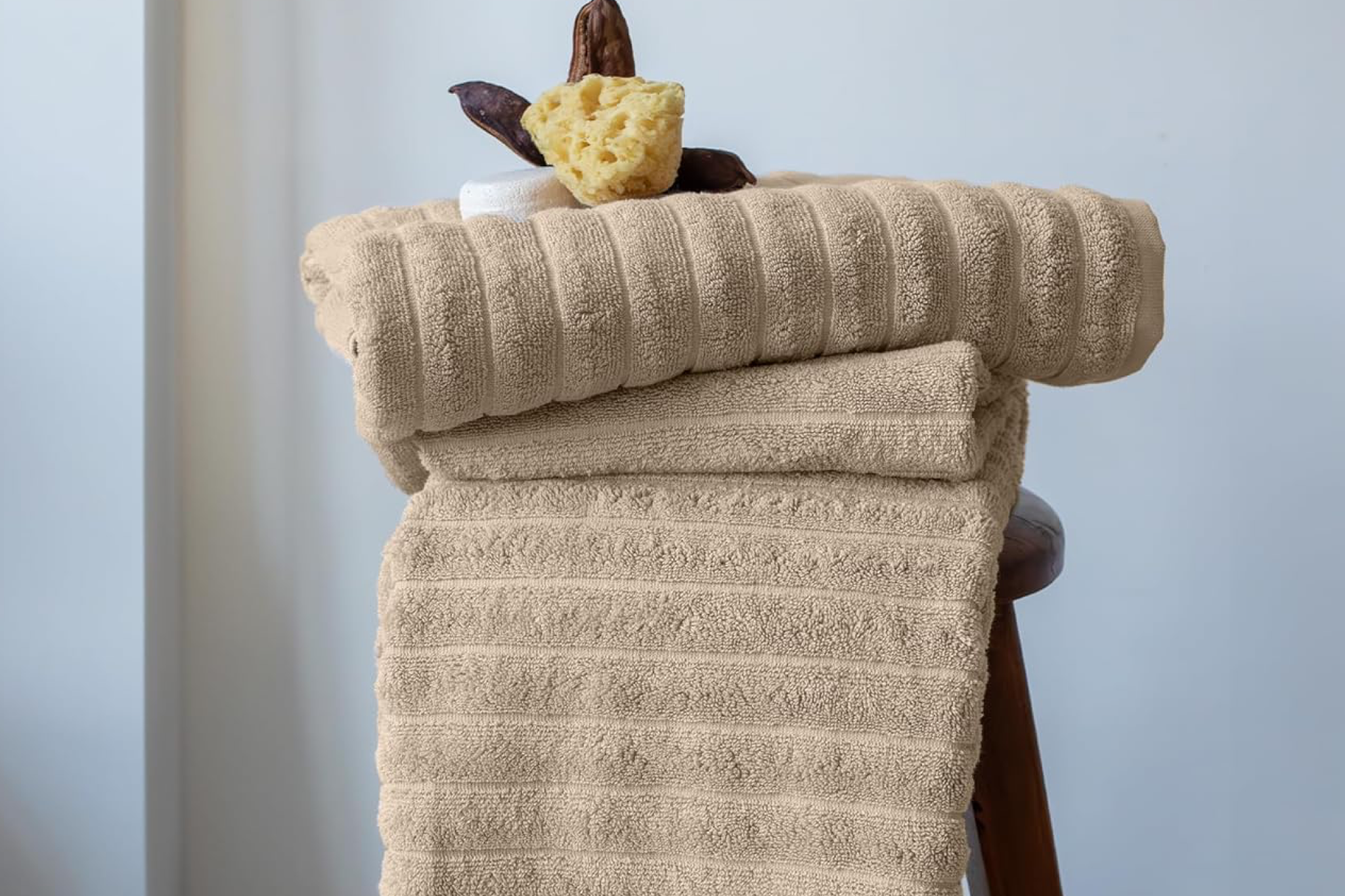 Beige Turkish cotton towels neatly folded on a wooden stool, showcasing classic softness and quick-drying comfort — one of the Best Quick-Dry Towels for the Beach.
