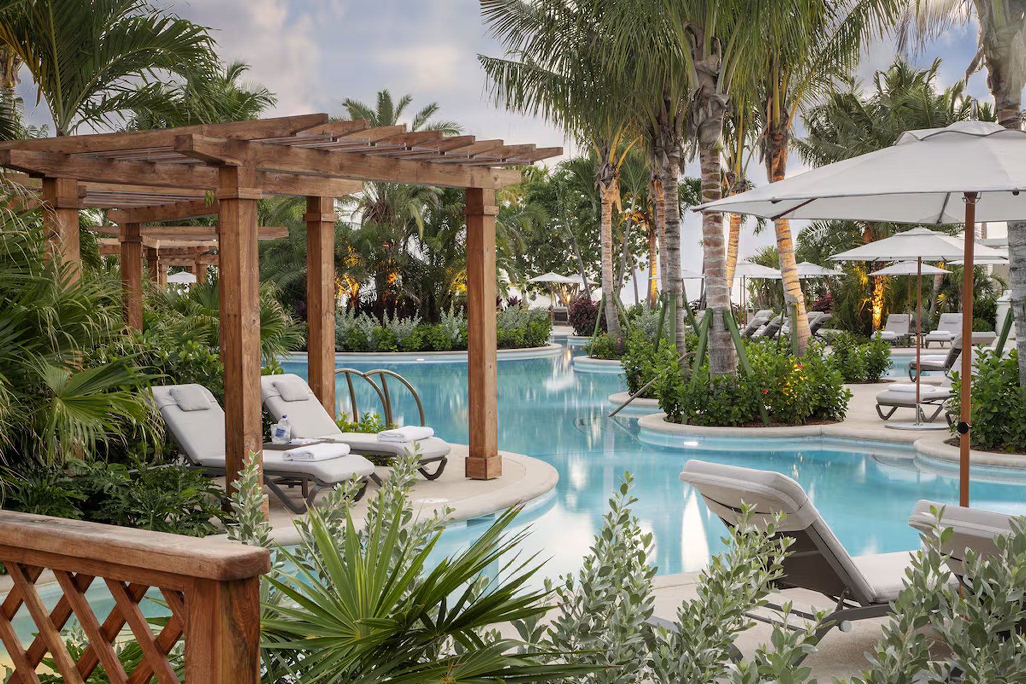 Tropical poolside area with loungers and wooden pergolas at Rosewood Baha Mar.