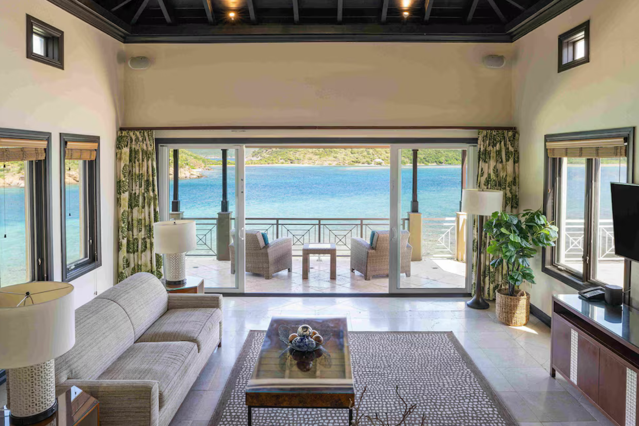 Spacious living room in a luxury suite at Scrub Island Resort Spa & Marina, opening to a balcony with panoramic ocean views.
