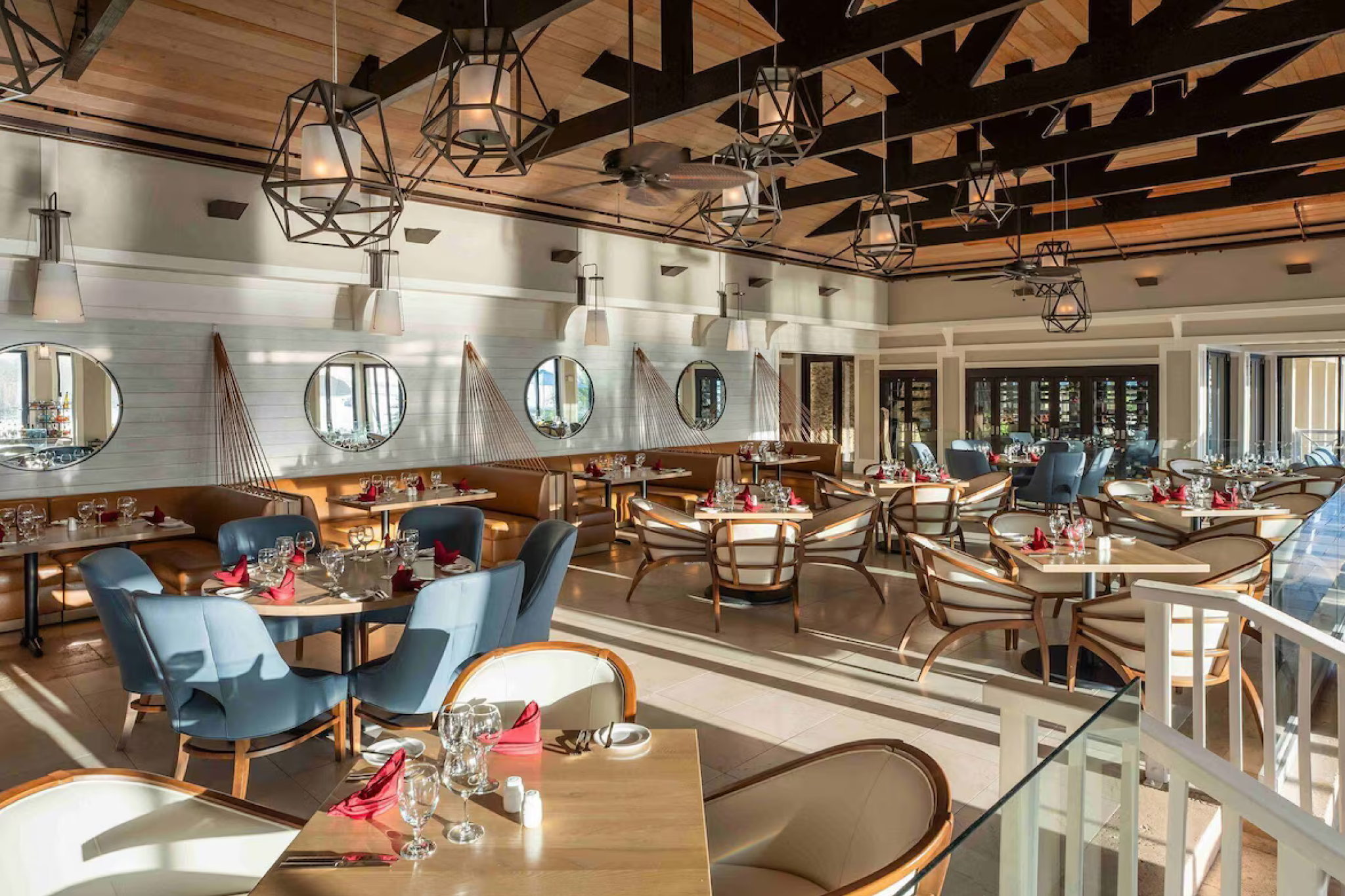 Elegant dining room at Scrub Island Resort Spa & Marina with modern lighting, neatly set tables, and large windows letting in natural light.