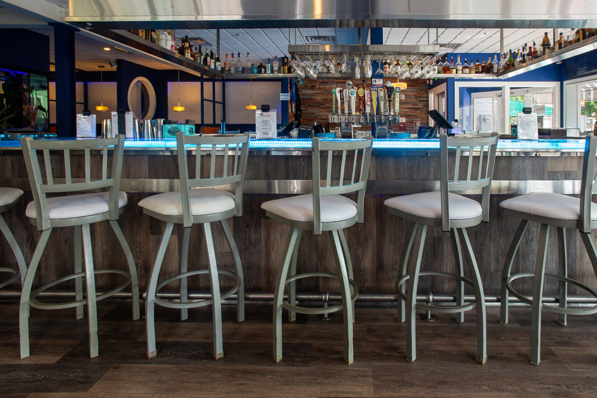 Modern coastal bar with blue lighting and tall stools inside Fins Bar & Grille, a lively pick among the Best Seafood Restaurants in Cape May for cocktails and creative fare.