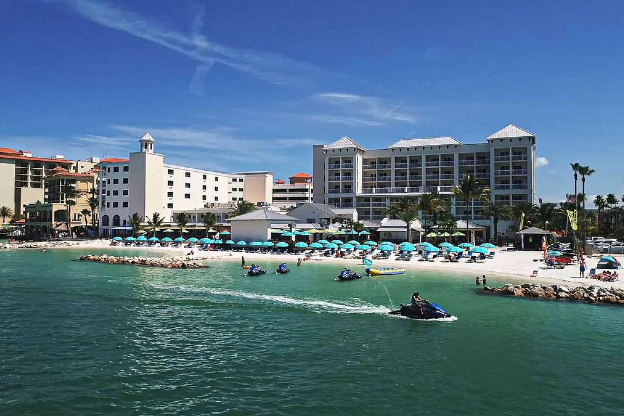 Guests enjoying water sports on jet skis near the shoreline in front of Shephard’s Beach Resort Clearwater on a sunny day.