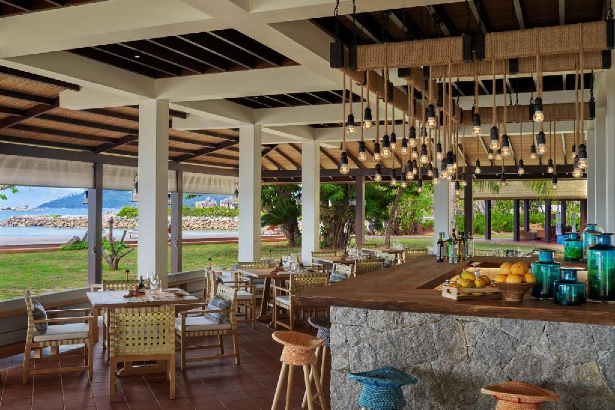 Open-air dining area at Six Senses Zil Pasyon with wooden furniture, decorative lighting, and views of the surrounding tropical greenery.