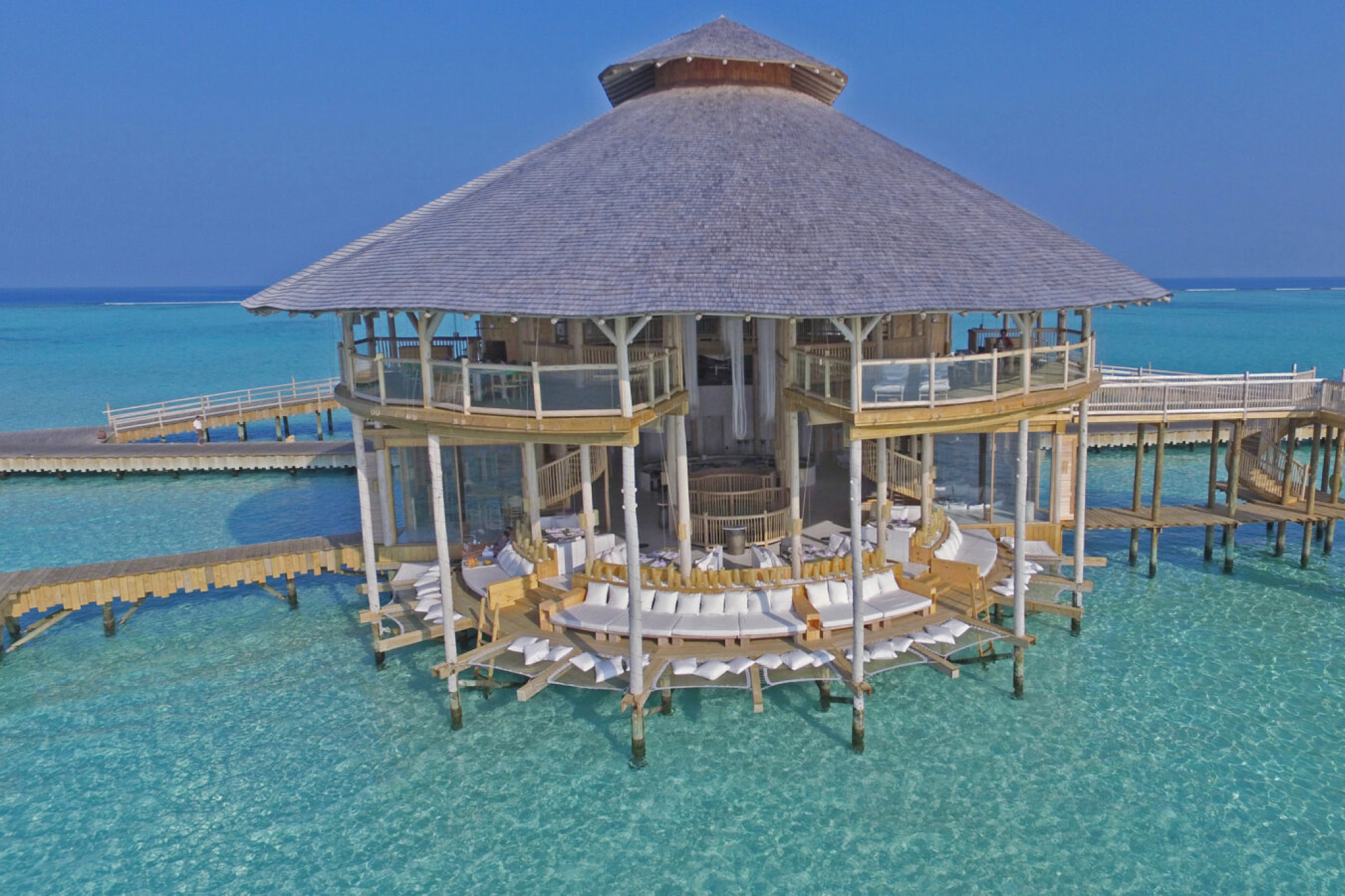 Overwater Dining Pavilion at Soneva Jani Two-story circular restaurant on stilts above the sea, featuring plush seating and uninterrupted views of the turquoise lagoon.