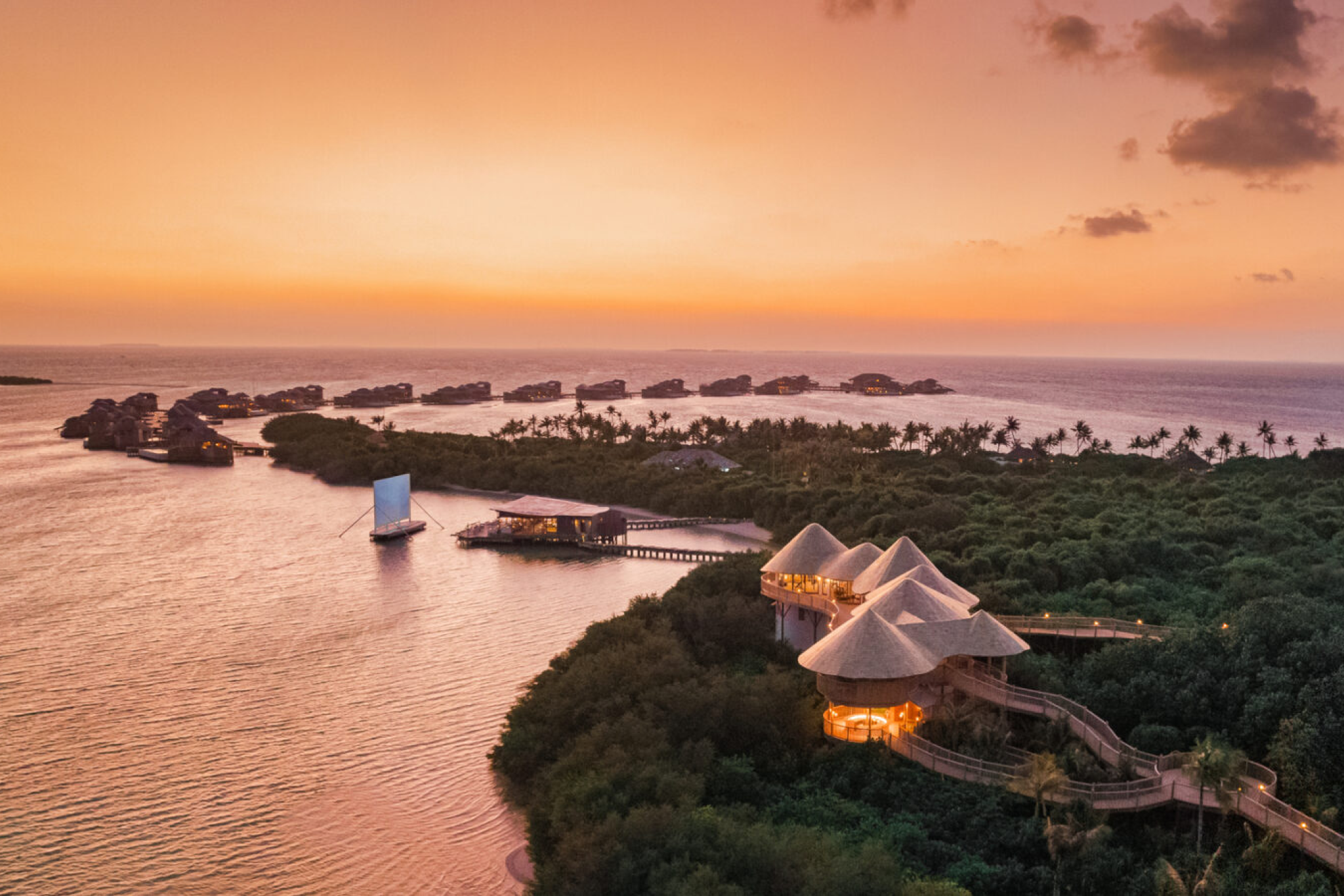Sunset view over Soneva Jani’s island with villas stretching into the water, highlighting the secluded layout of the resort.