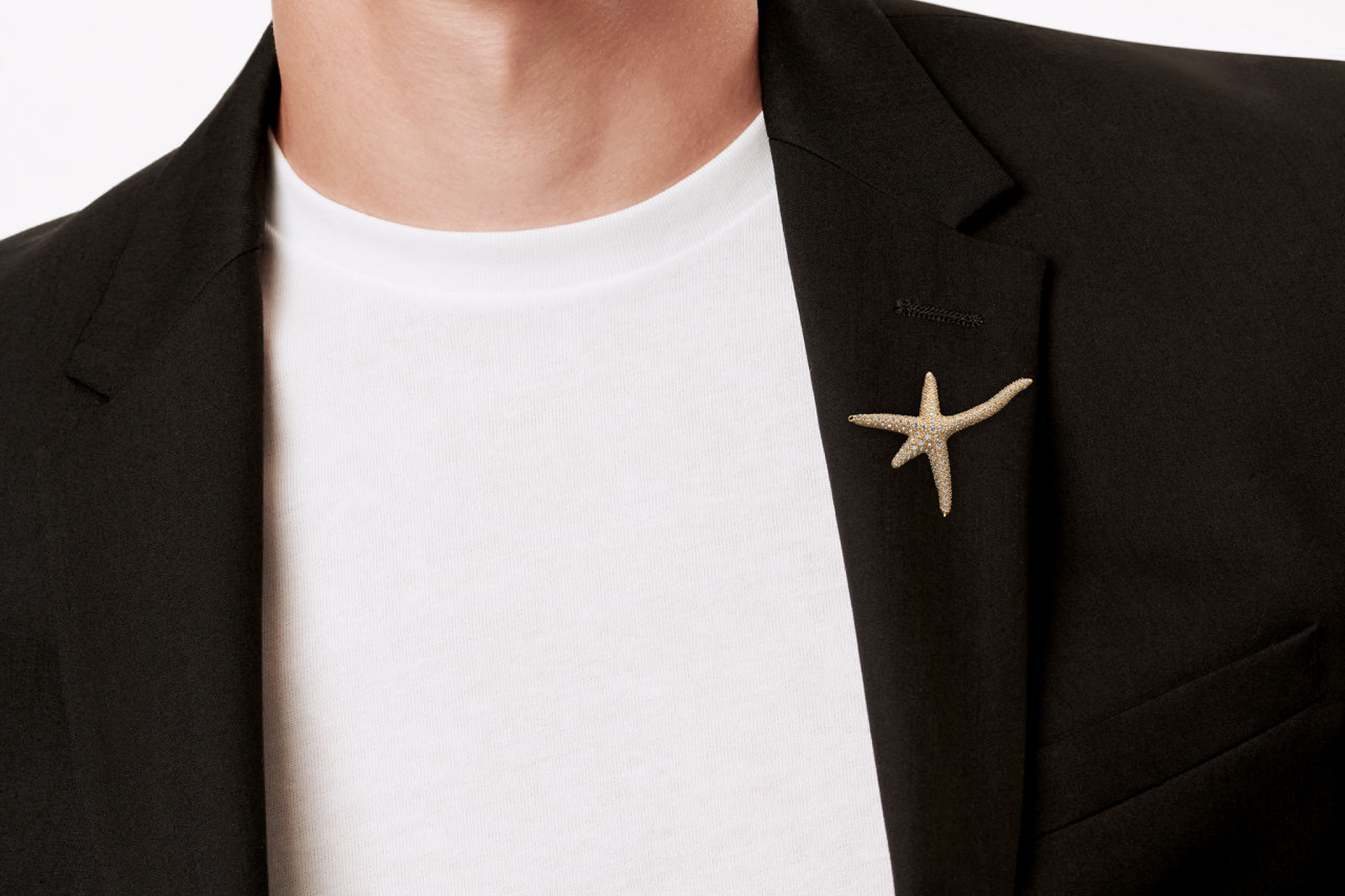Elsa Peretti Starfish Brooch in Yellow Gold with Pavé Diamonds styled on a black blazer lapel, highlighting its elegant statement appeal.