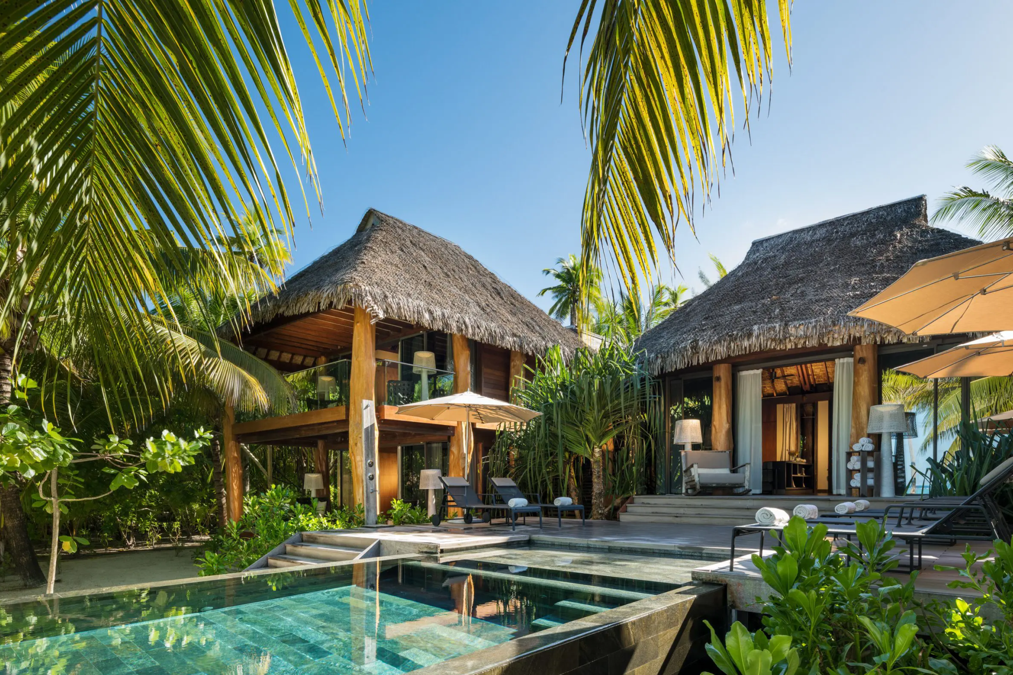 Thatched-roof villas at The Brando blending into tropical foliage, showcasing the resort’s eco-conscious architecture and natural materials.
