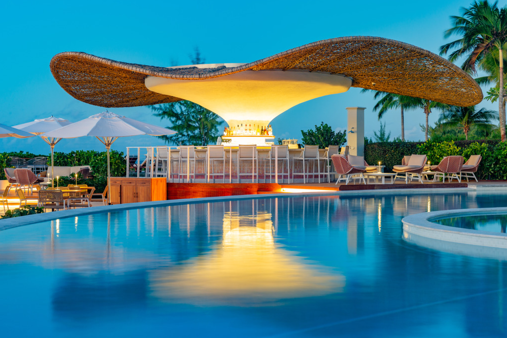 Evening view of The Palms Turks and Caicos poolside bar with modern canopy design and seating
