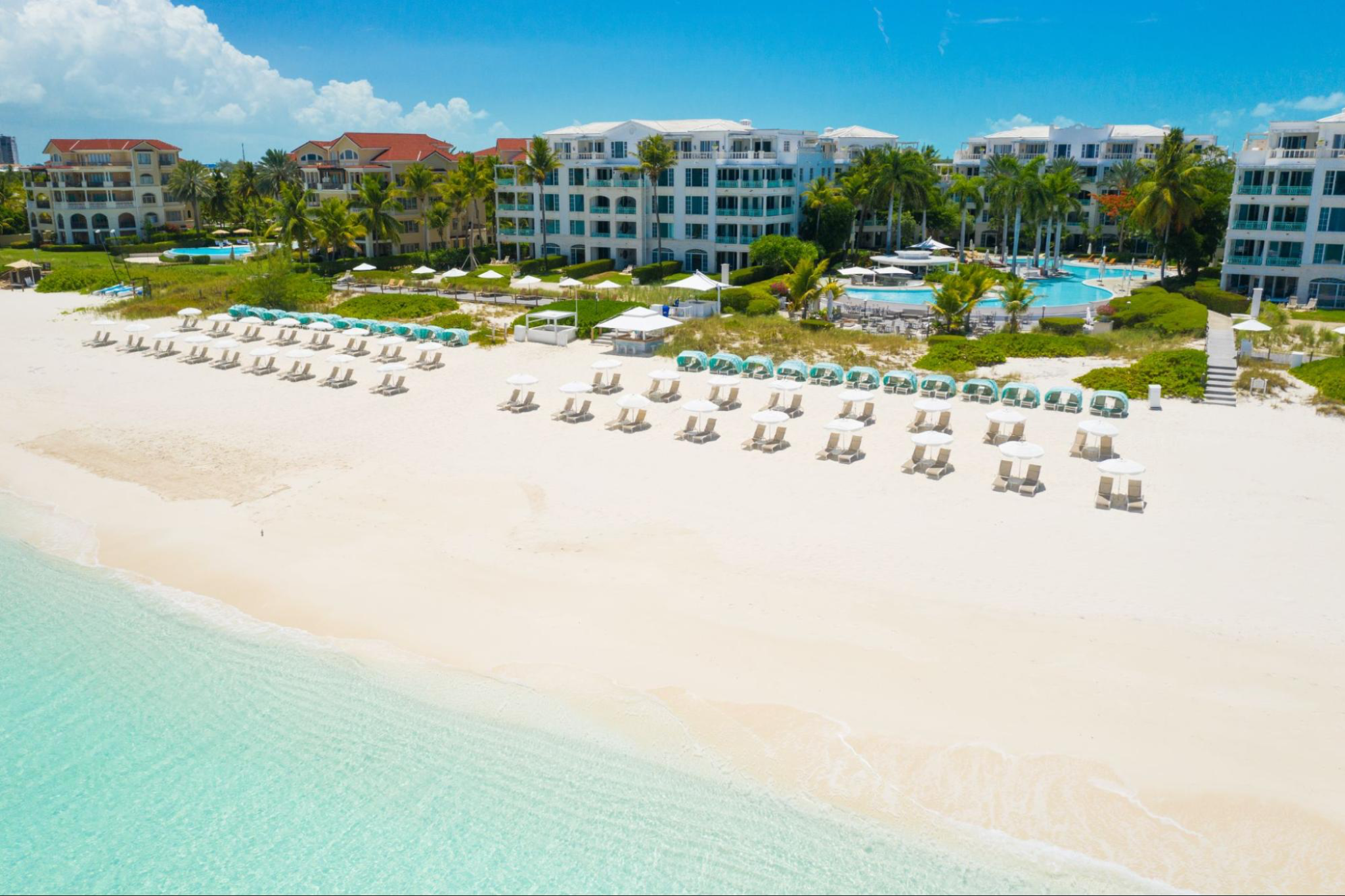 Aerial view of The Palms Turks and Caicos with beachfront loungers and turquoise waters on Grace Bay Beach